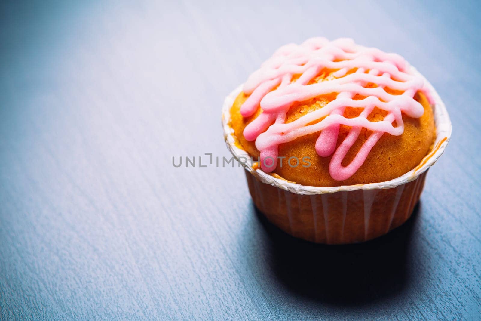 cupcake with pink frosting on a wooden background