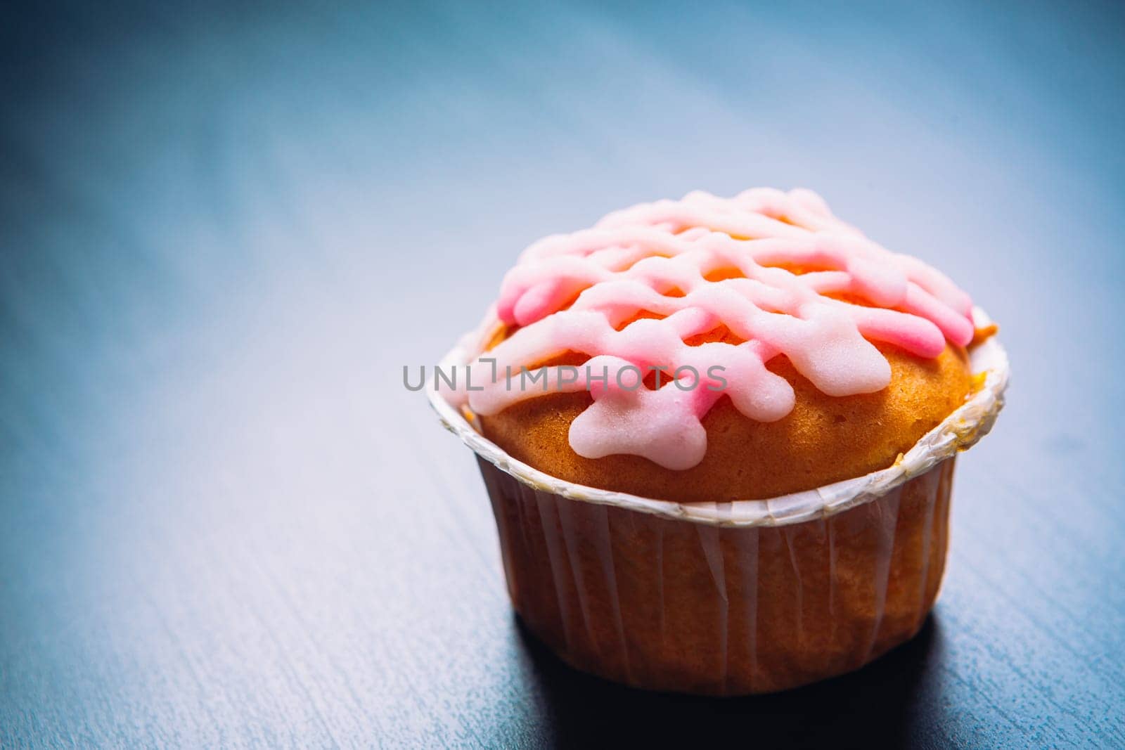 cupcake with pink frosting on a wooden background