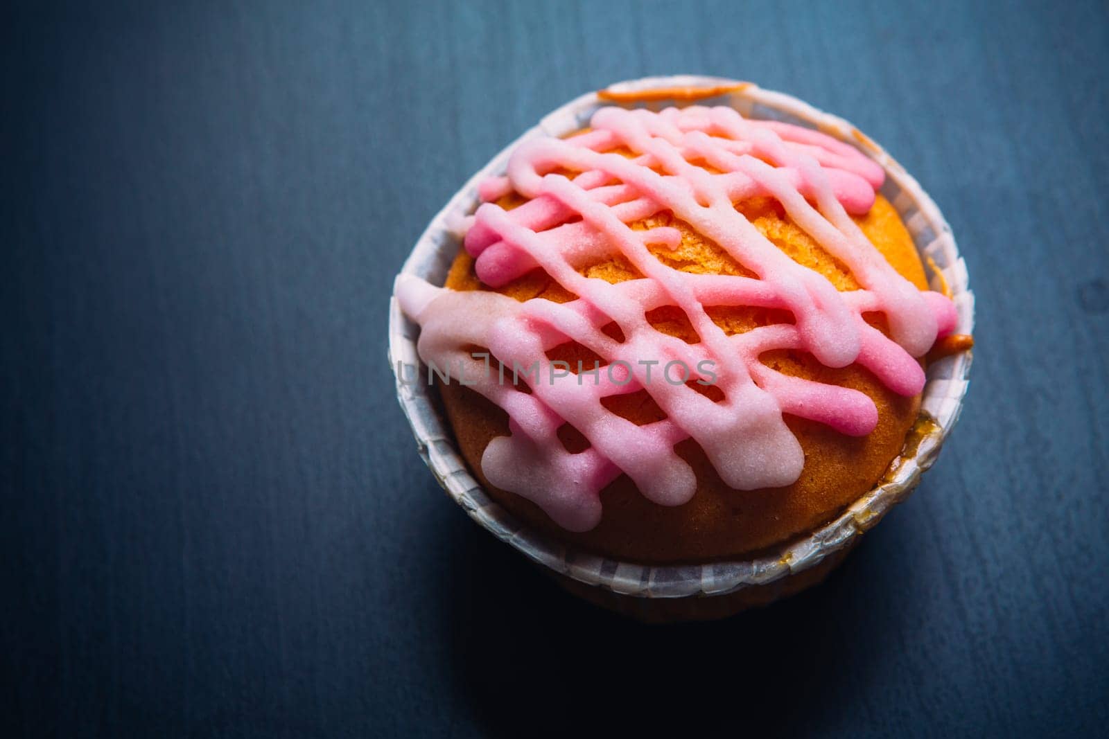 cupcake with pink frosting on a wooden background