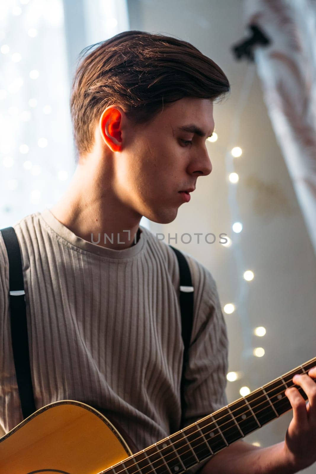 Young man sitting at home and playing guitar dramatic