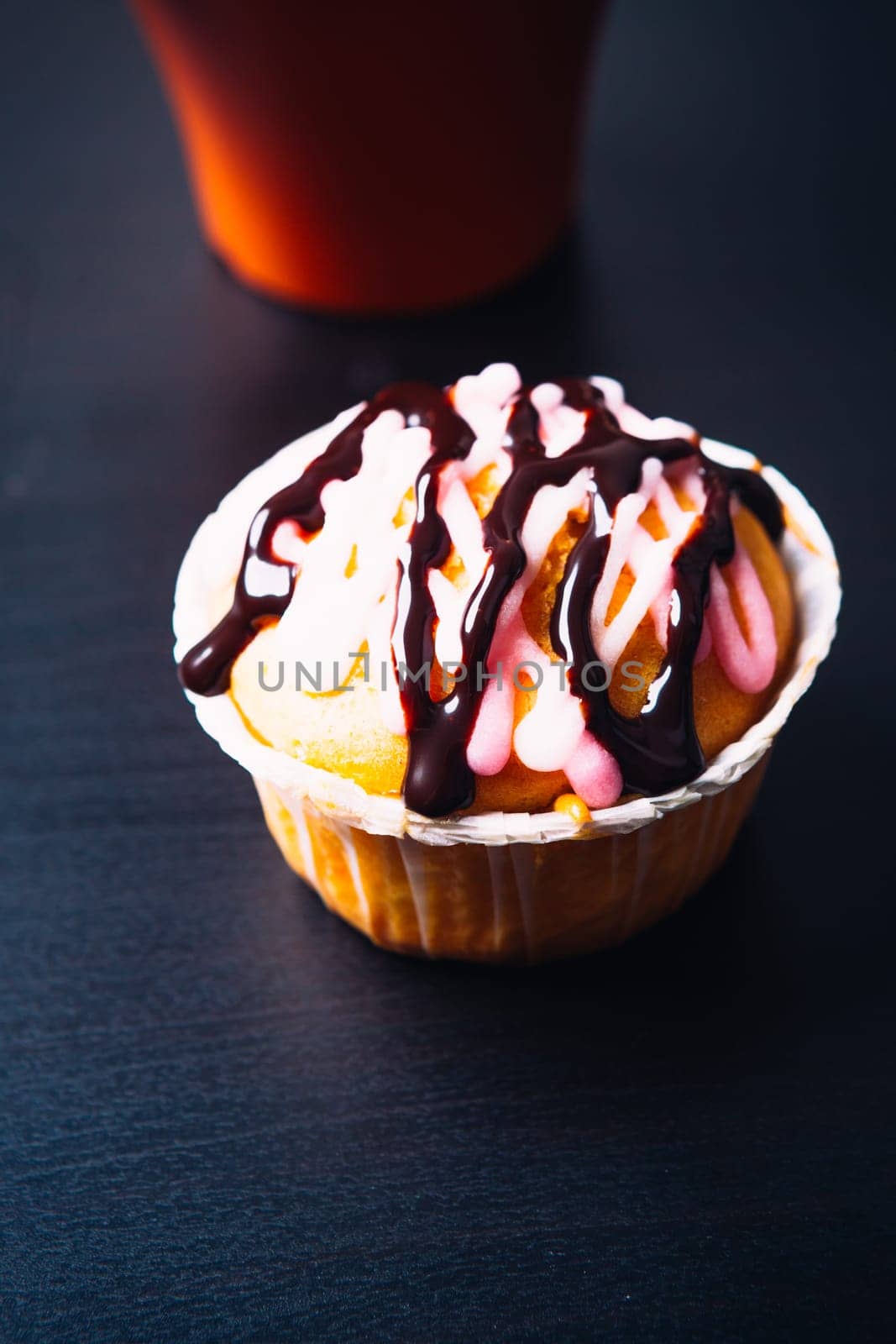 cupcake with pink frosting and red cup on a wooden background