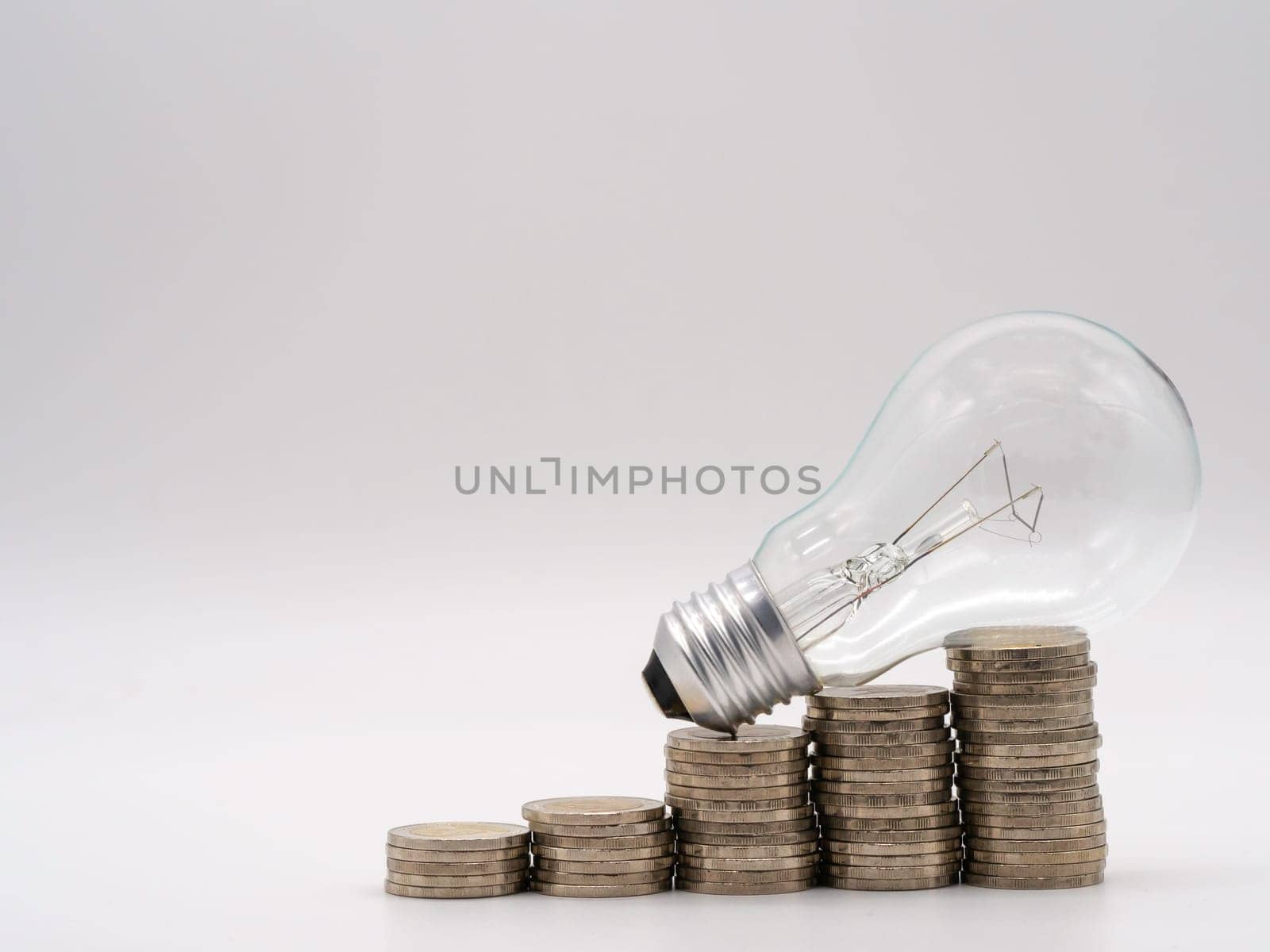 Energy saving light bulb with stacks of coins for financial, accounting and saving concept.