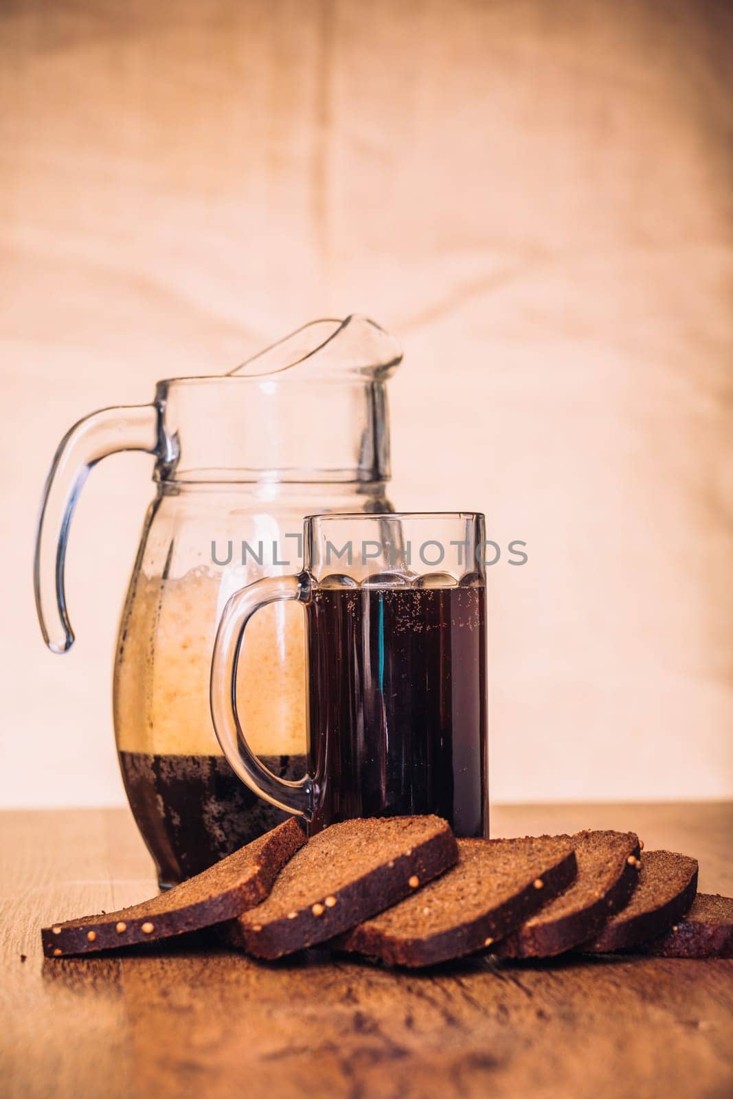 Russian brew in mug jug and loaf of rye flour on wooden background