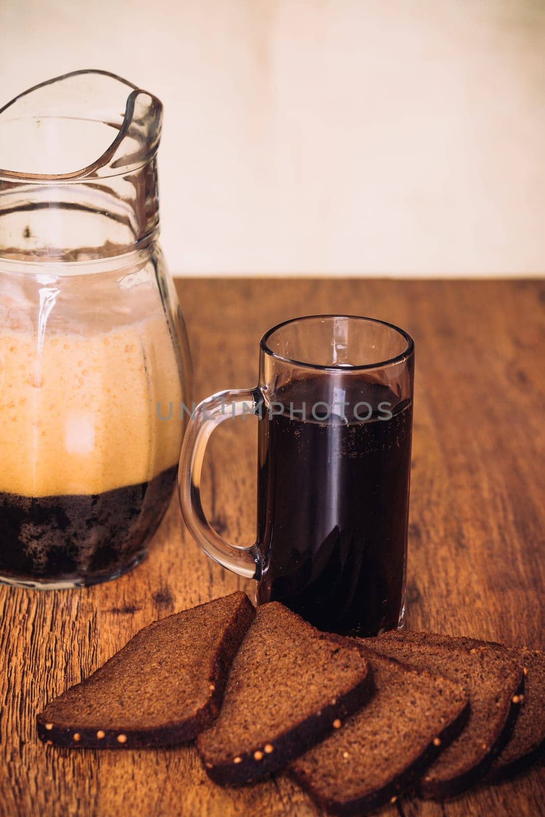 Russian brew in mug jug and loaf of rye flour on wooden background