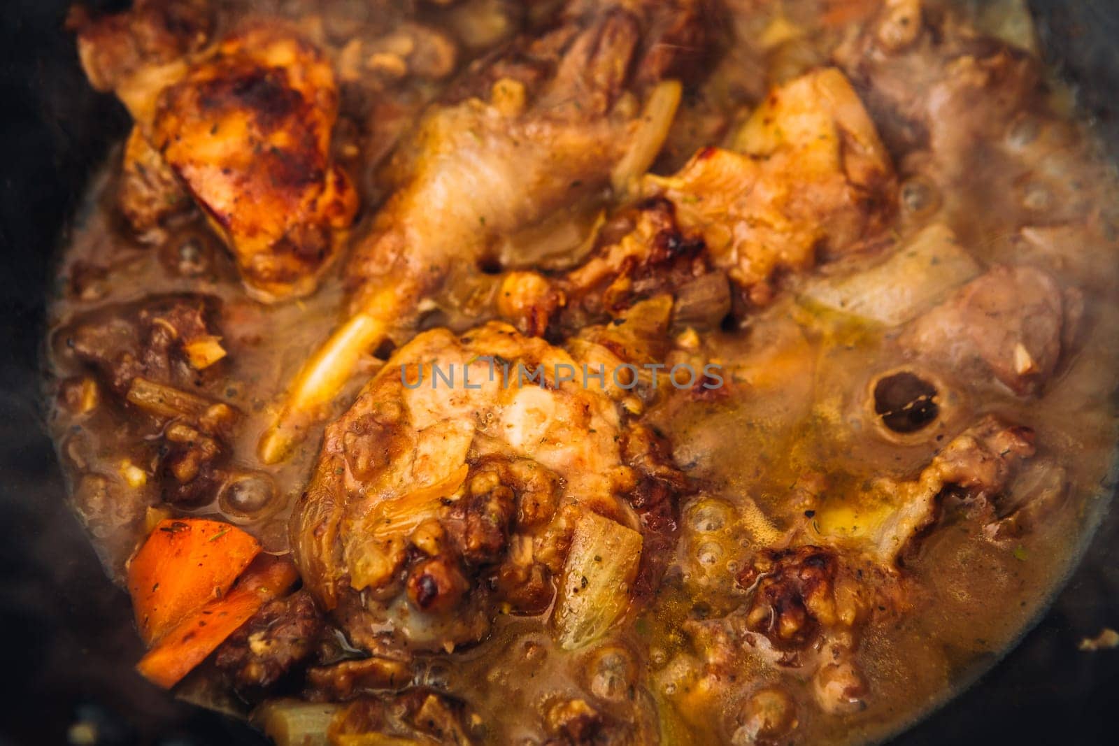 chicken in sauce with carrots in a pan closeup