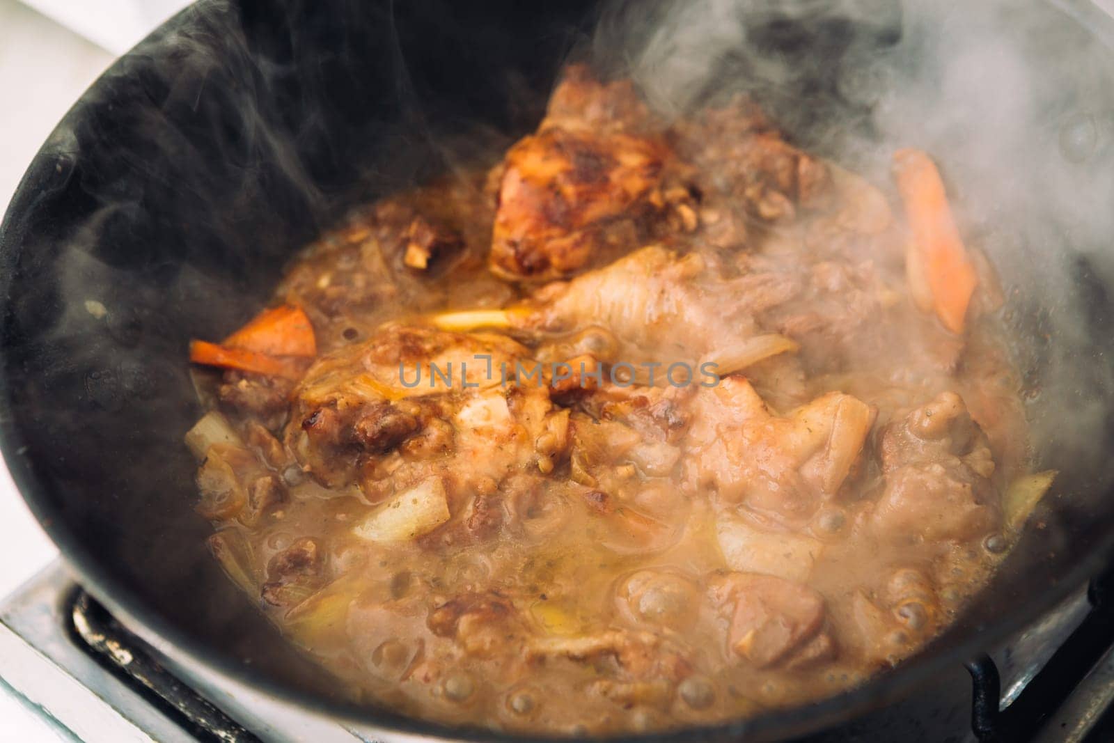 chicken in sauce with carrots in a pan closeup