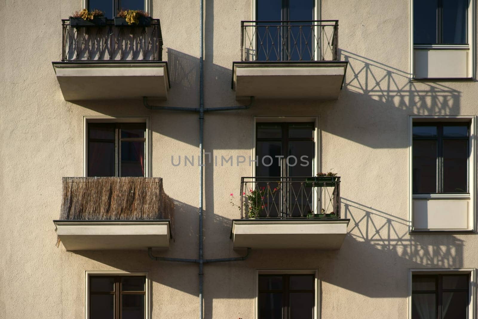 The railings of small nostalgic balconies of an apartment building cast shadows.
