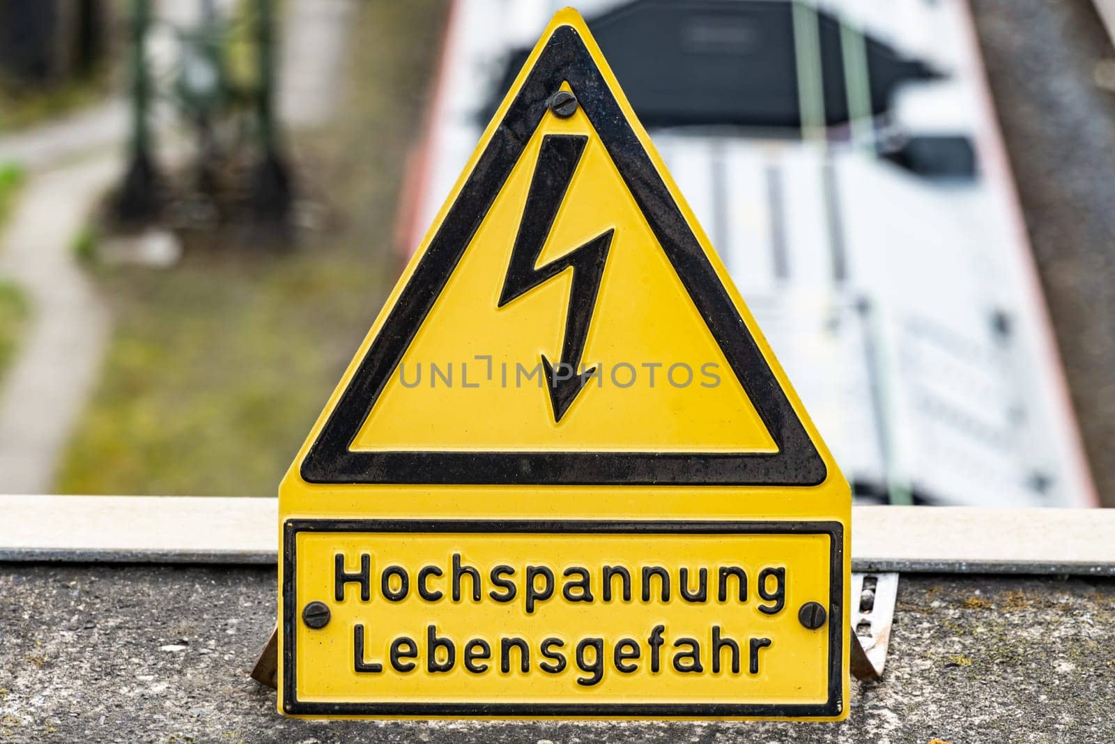 Close-up of a yellow high voltage caution sign mounted on a wall