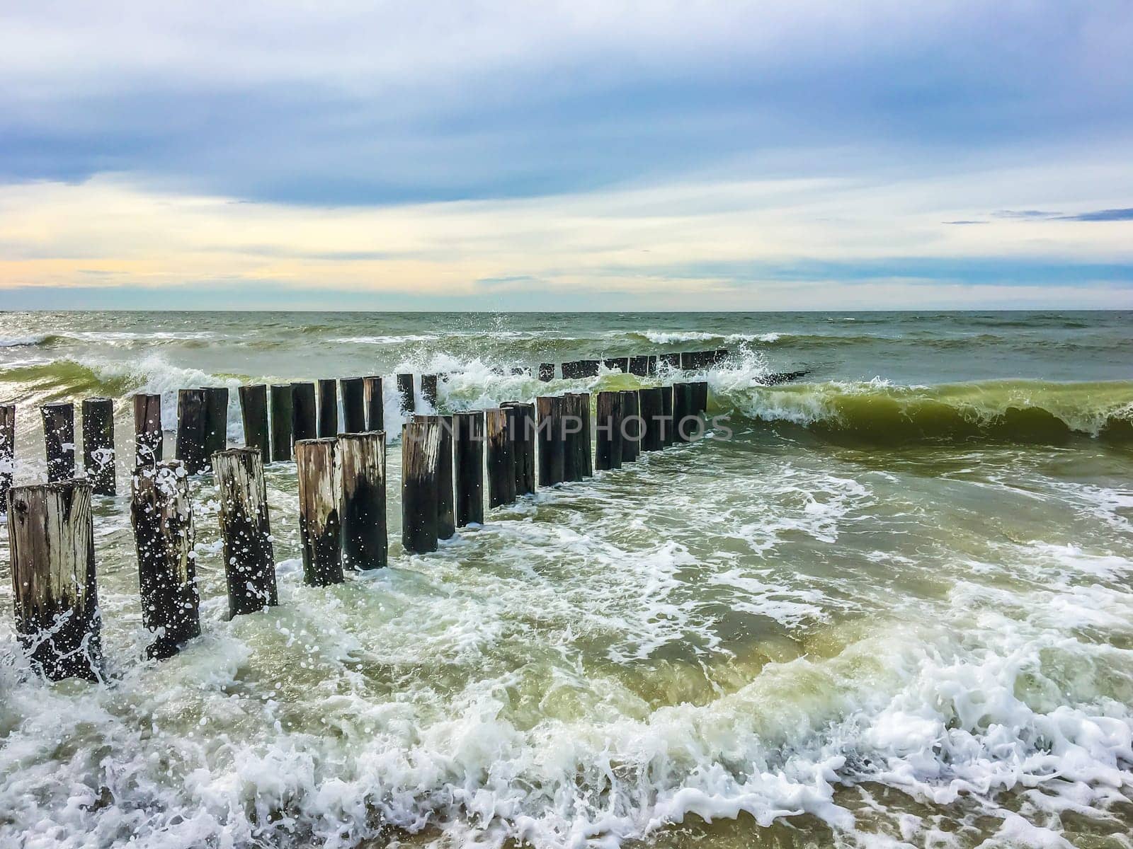 Wild ocean sea landscape with waves collapsing against wooden poles