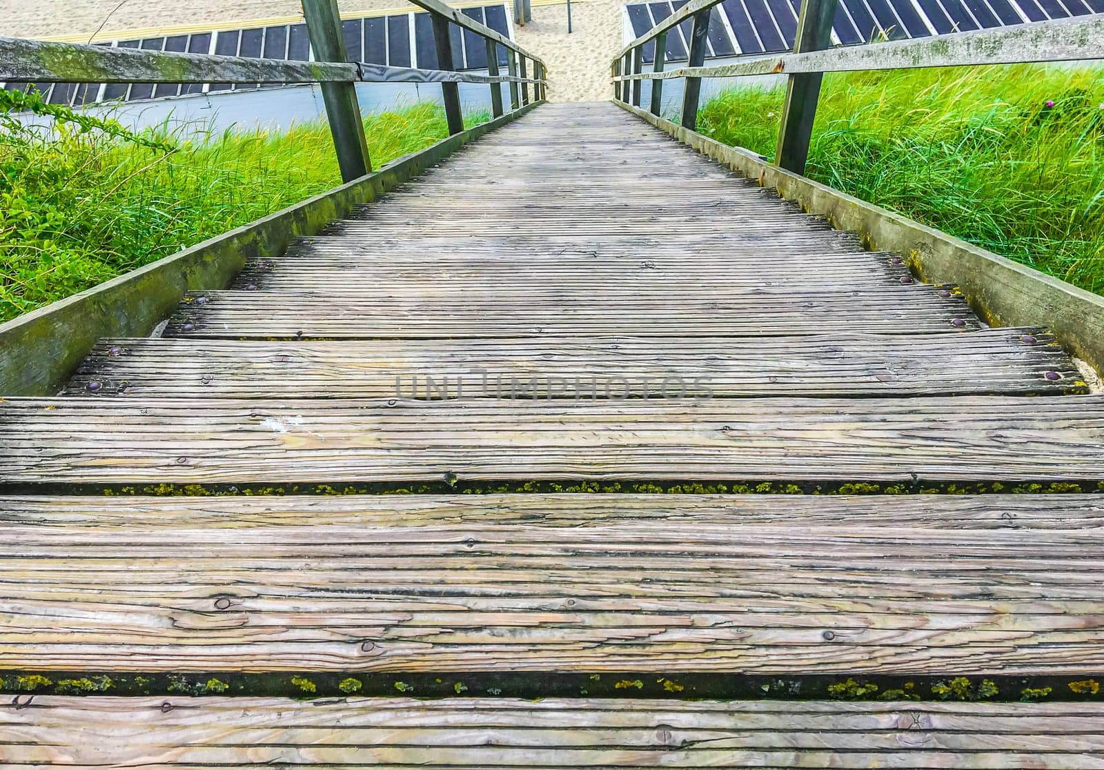 Downwards wooden staircase with railing leading to the beach