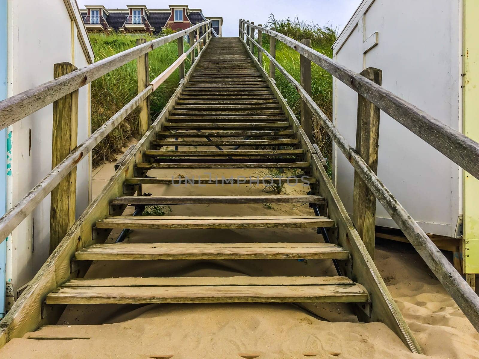 Upwards wooden staircase with railing in a beach landscape scene