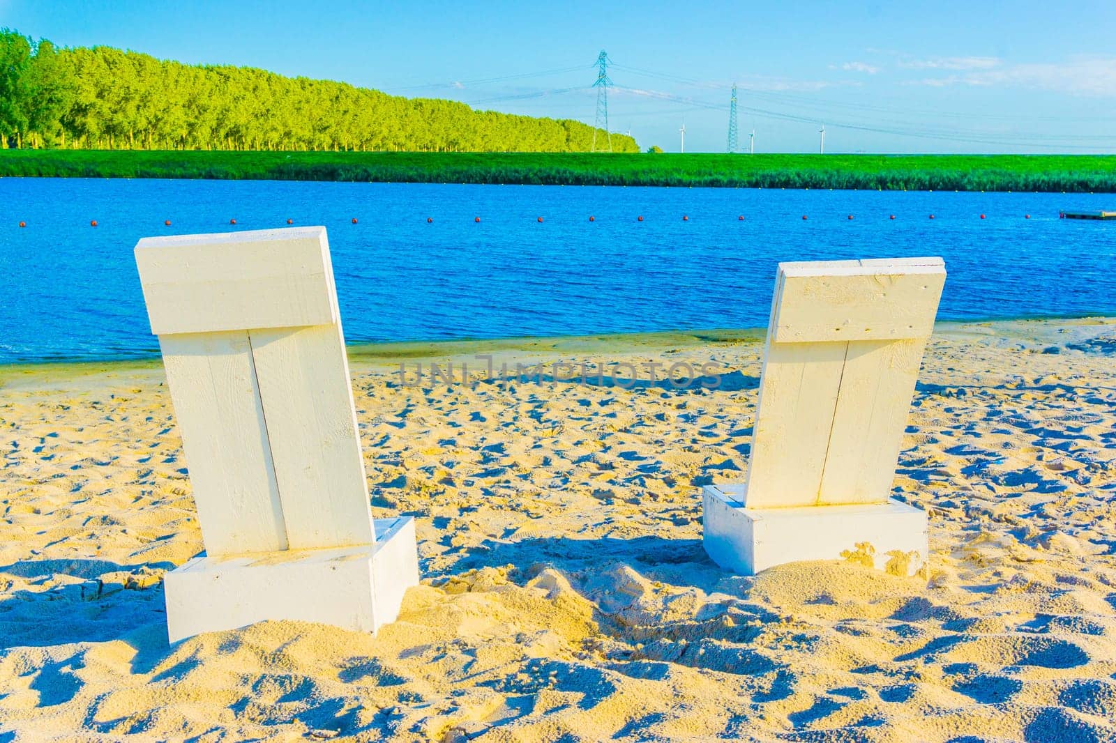 two white beach seats at a sandy beach river landscape