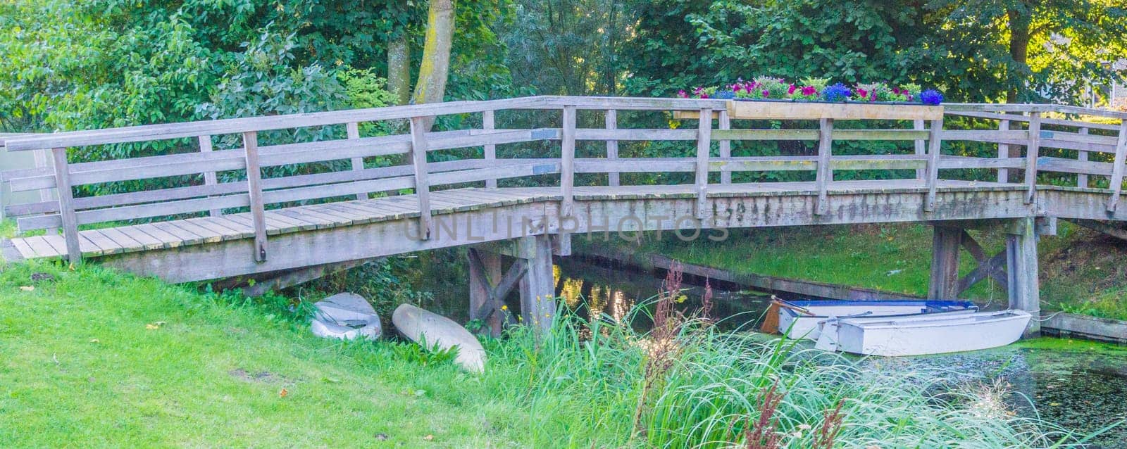 big wooden bridge with boats in a river landscape