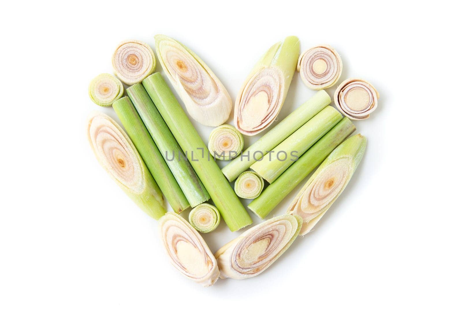 Fresh green lemongrass slices form a heart shape, isolated on white background.