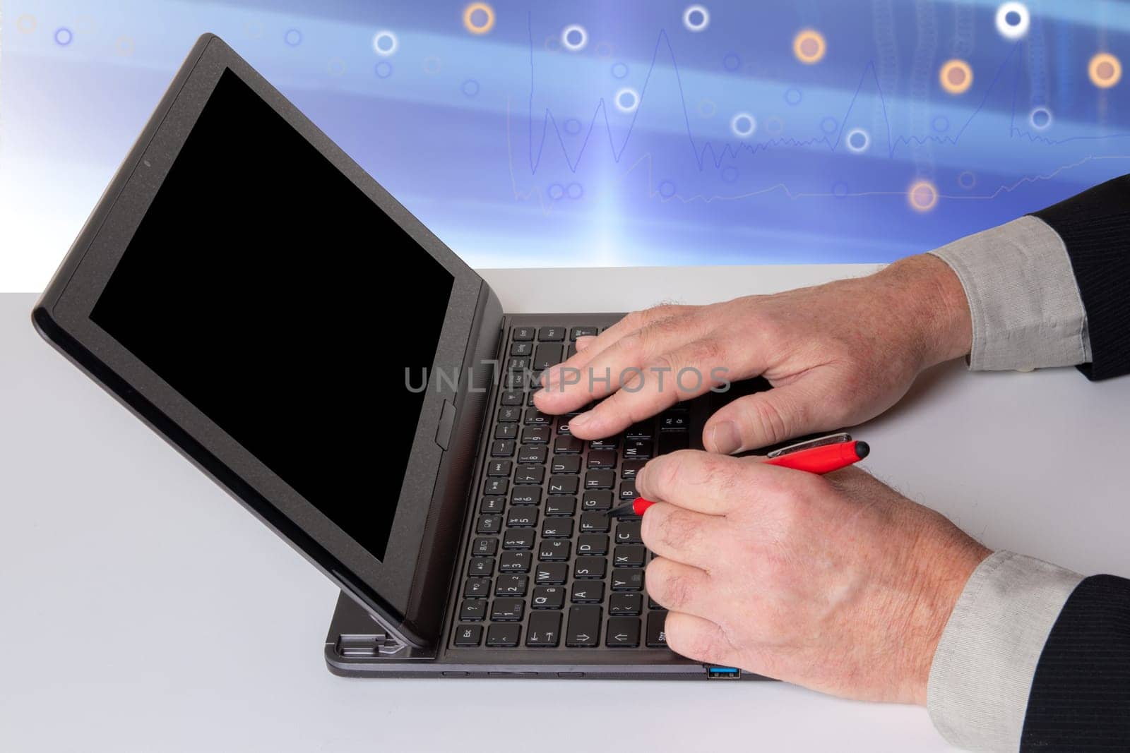 Hands of a unrecognizeable businessman working with  a modern portable computer on a white table. Computer in front of abstract bright technology background.