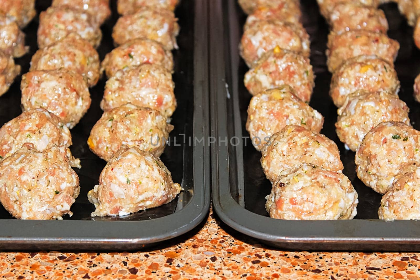 view of raw turkey pine nut meatballs on cookie sheets.