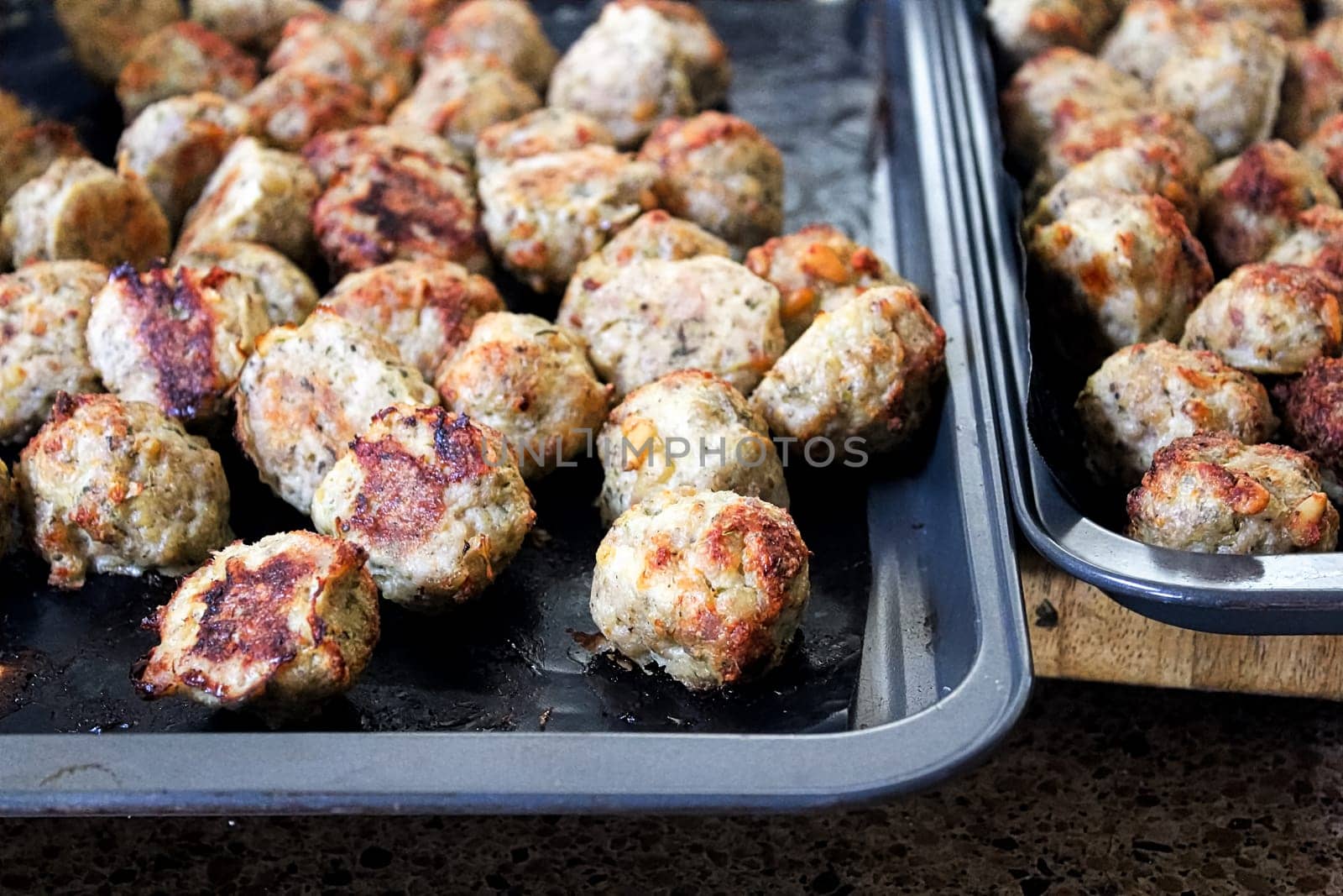 Freshly baked meatballs about to be taken off a cookie sheet.