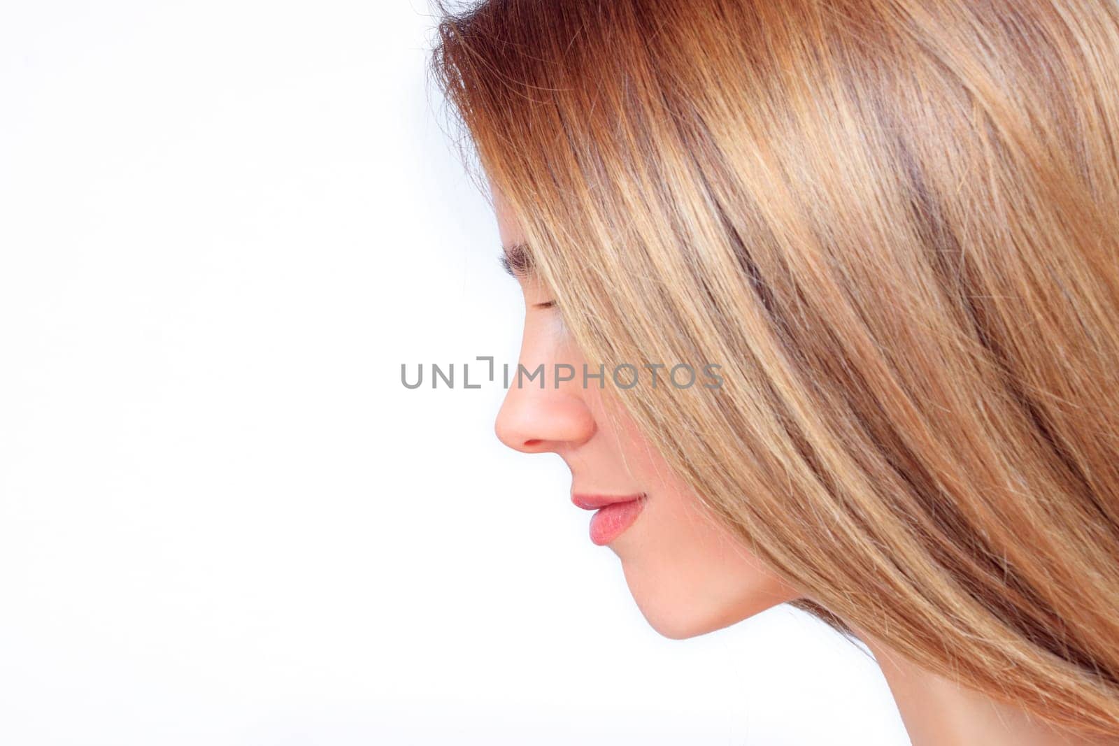 Beautiful woman face with long blond hair from the side looks down