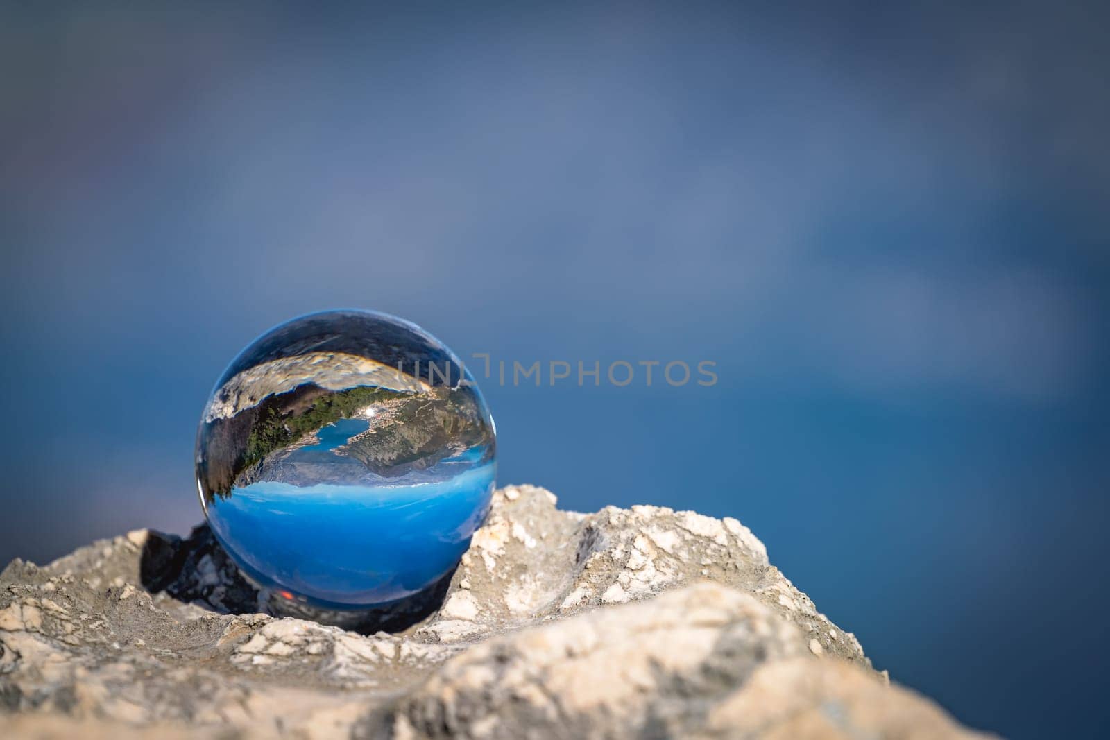 Stunning landscape of the Bay of Kotor and Lovcen National Park in Montenegro reflected in a large glass ball placed on a large boulder