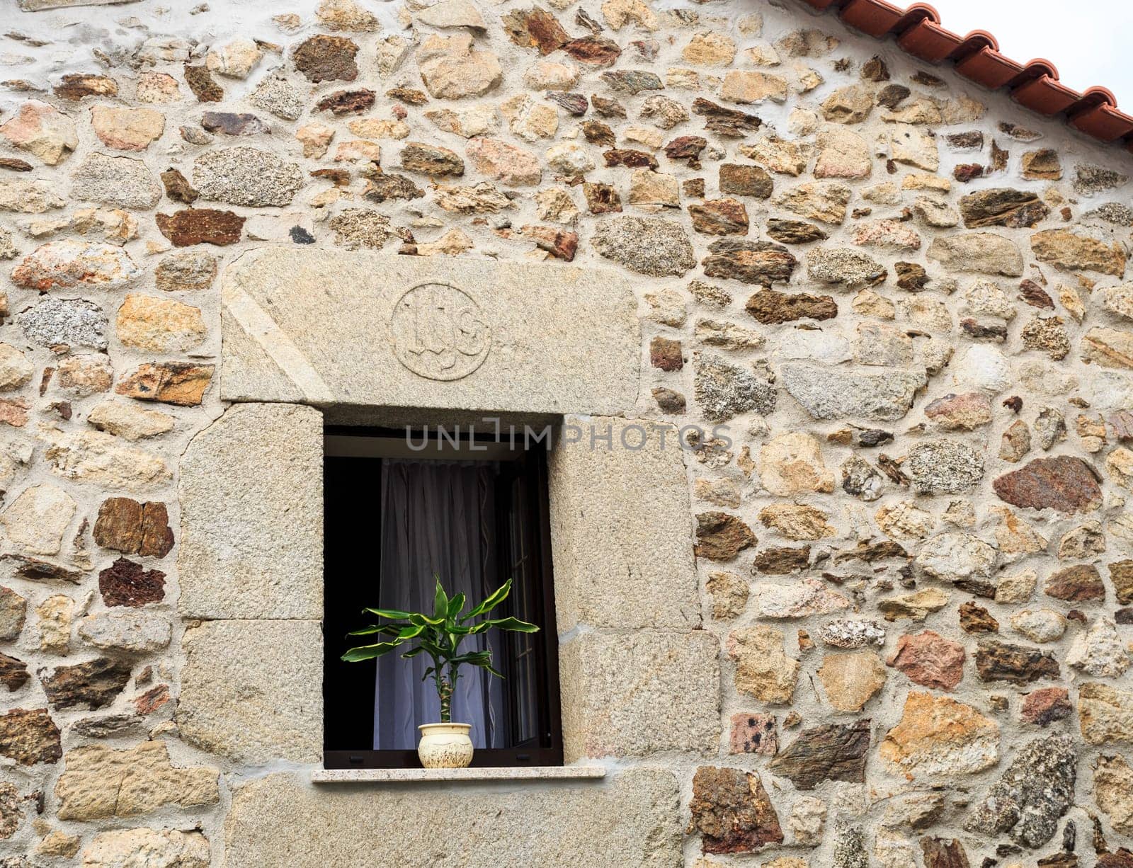 Vase with plant on a beautiful stone framed window in the historic village of Linhares da Beira, Gouveia, Portugal
