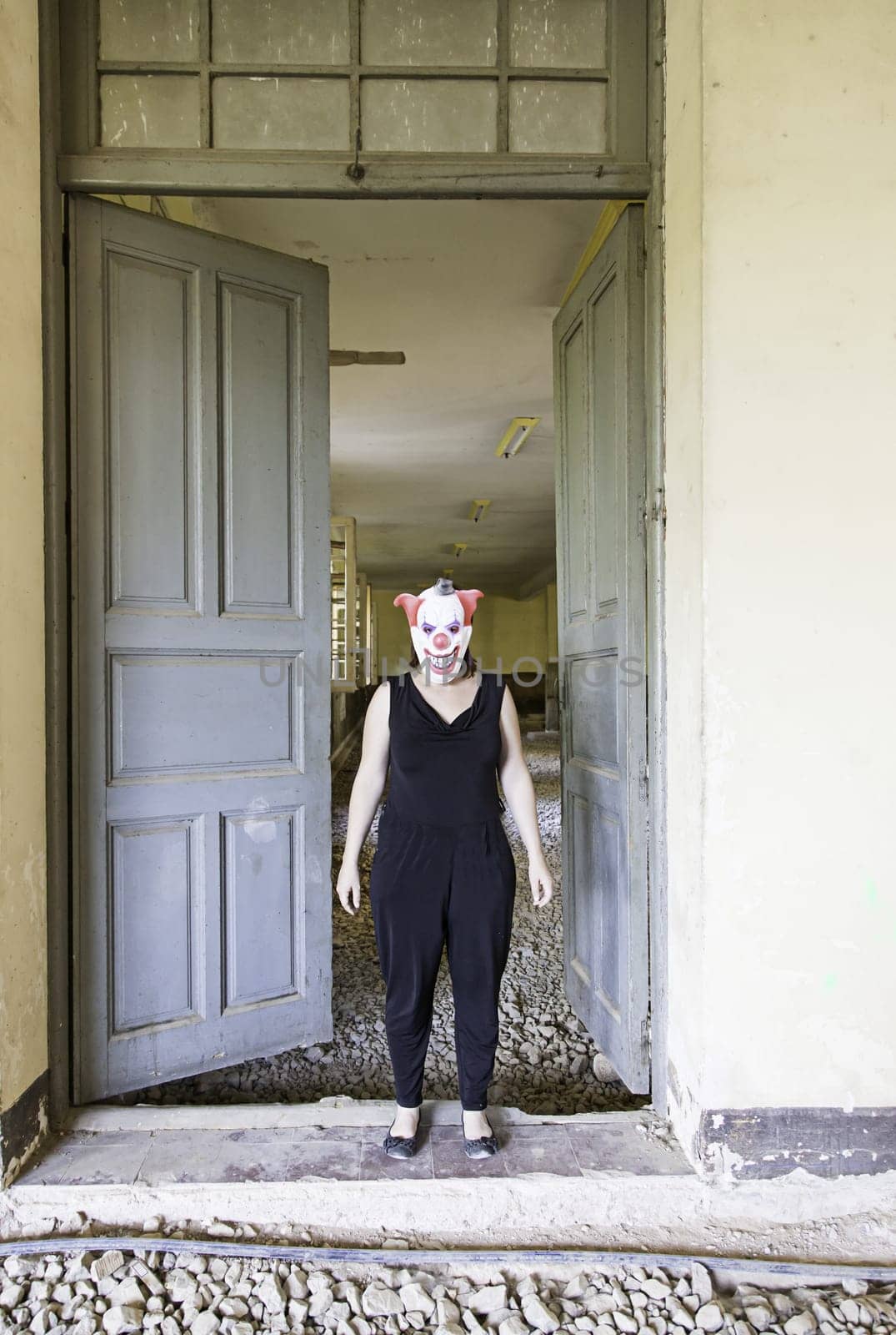 Clown in abandoned house door, fear and halloween