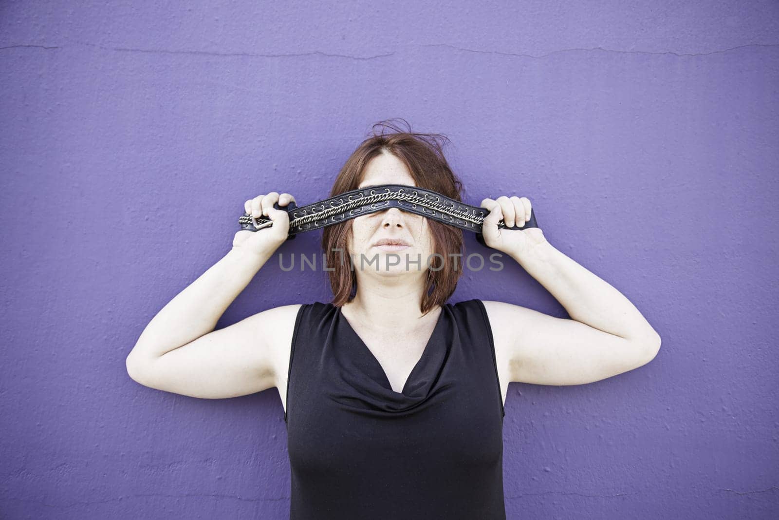 Girl covering eyes with tape on wall, mystery