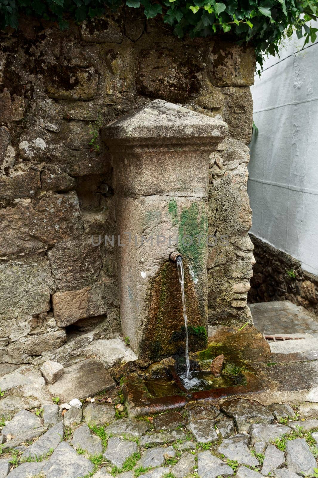 Small fountain with continuous running water found in a narrow street of Linhares da Beira, Beira Alta, Portugal