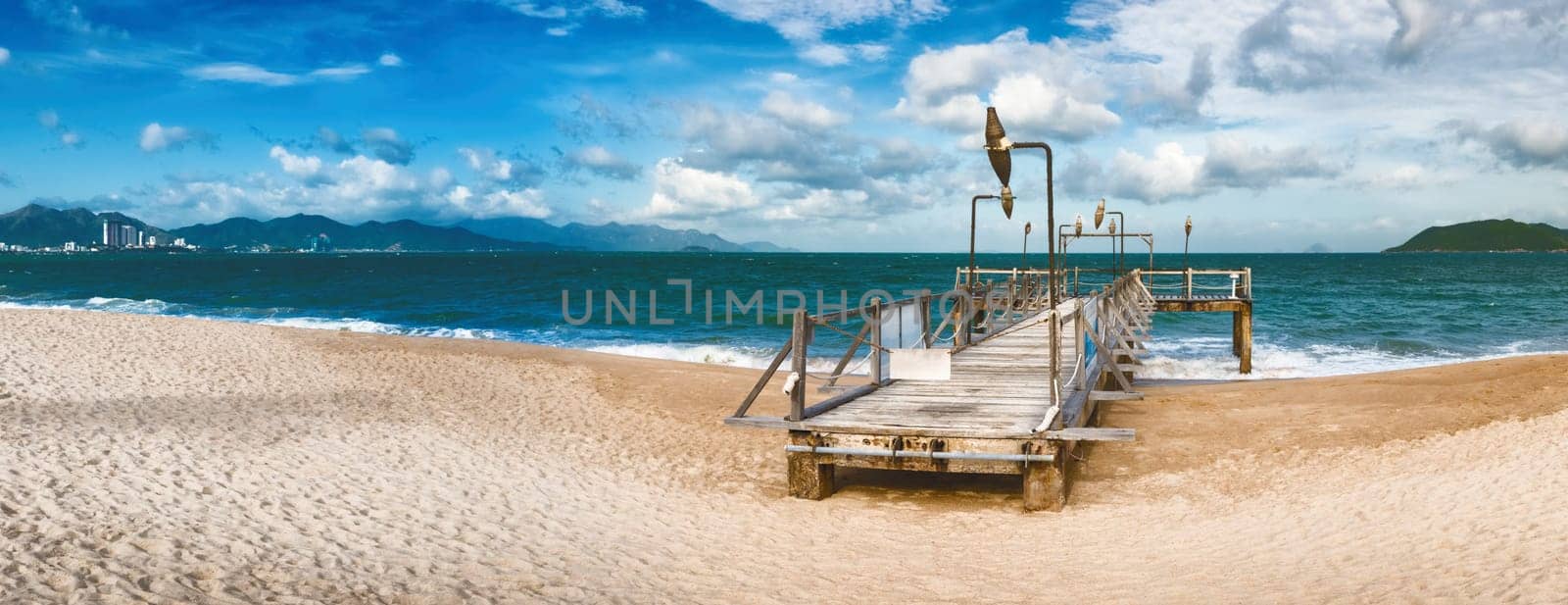 Scenic view of Nha Trang beach at sunny day. Beautiful tropical landscape. Pier on the foreground. Panorama