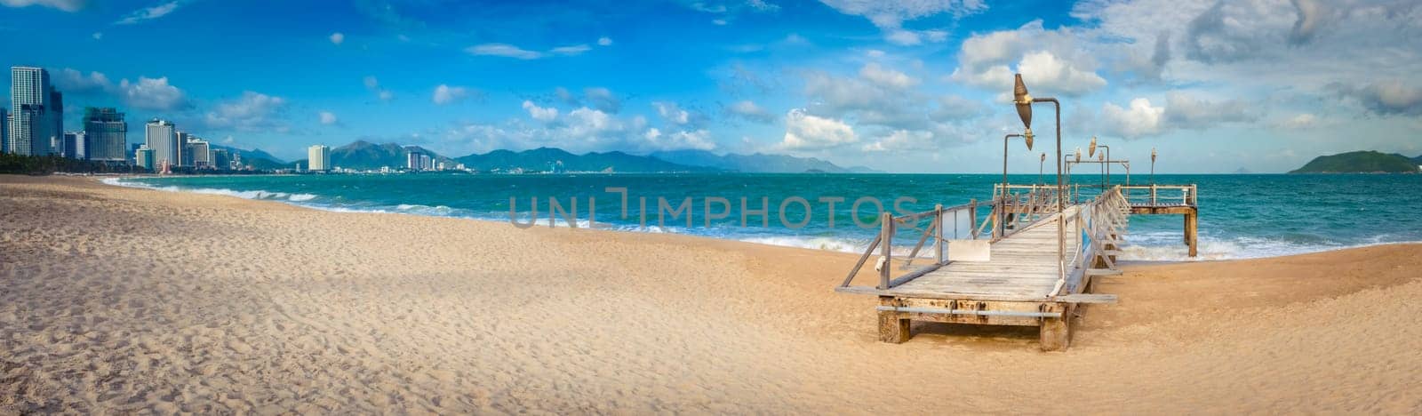 Scenic view of Nha Trang beach at sunny day. Beautiful tropical landscape. Pier on the foreground. Panorama