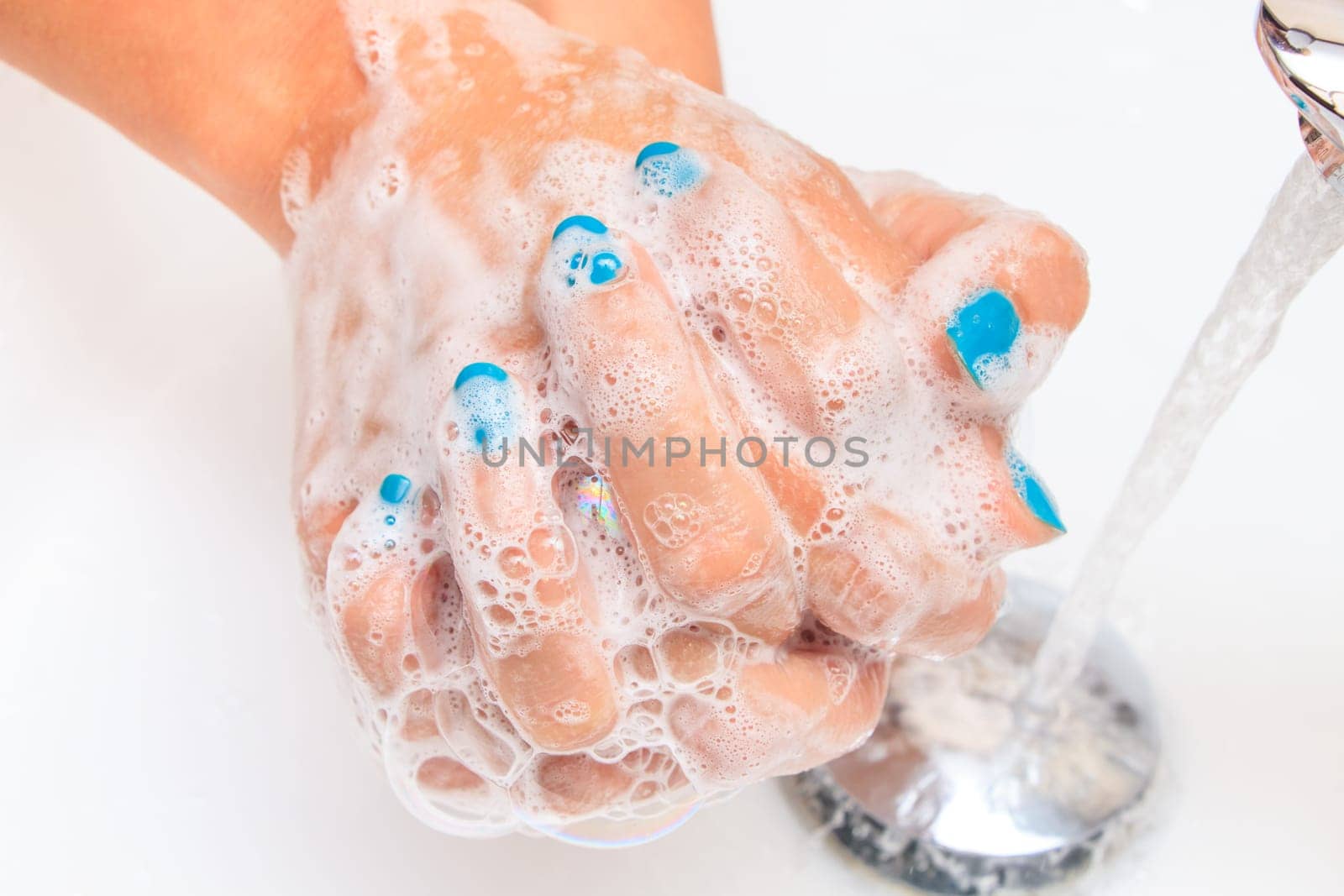 Female hands under running water in the sink