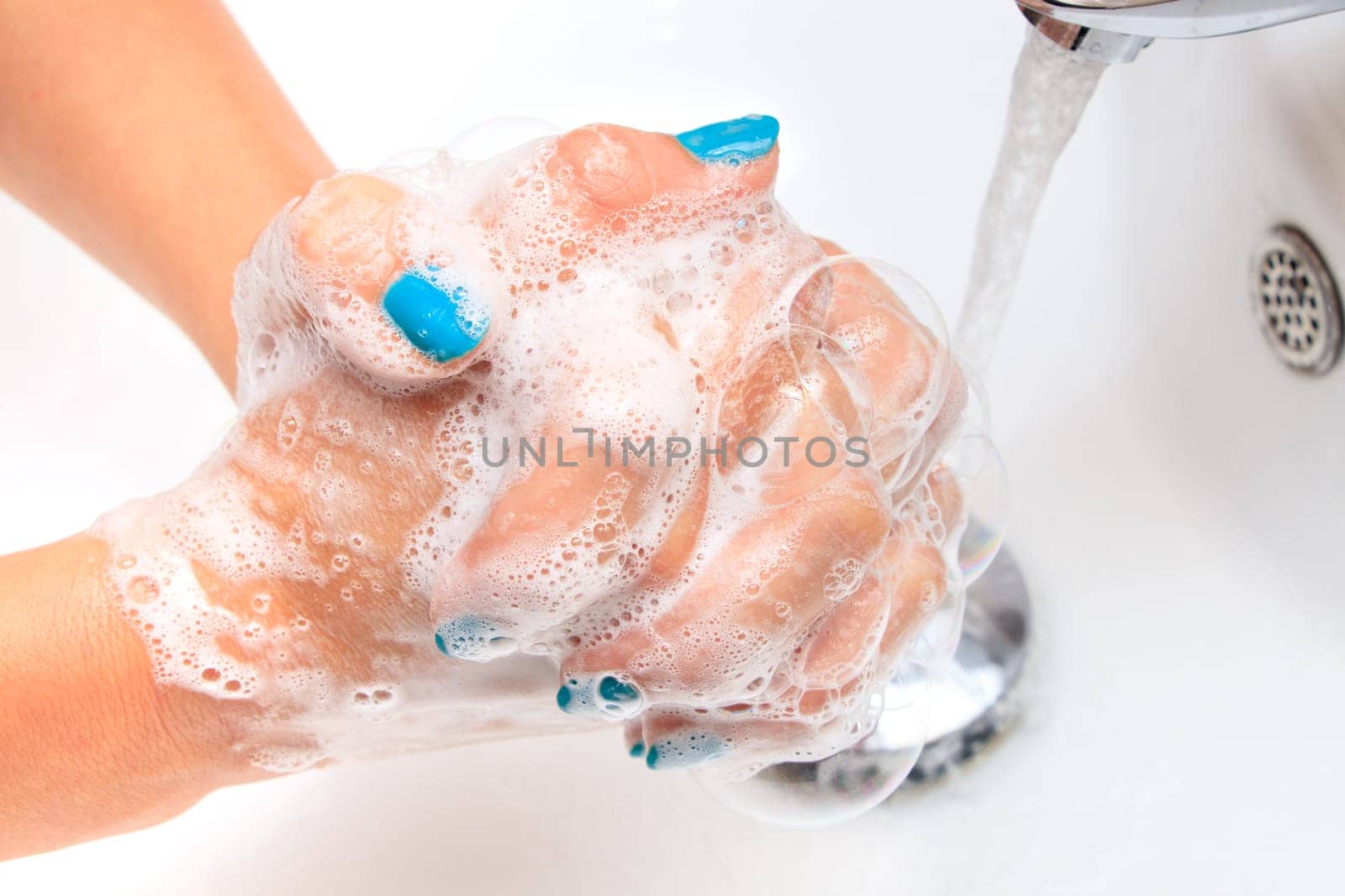 Female hands under running water in the sink