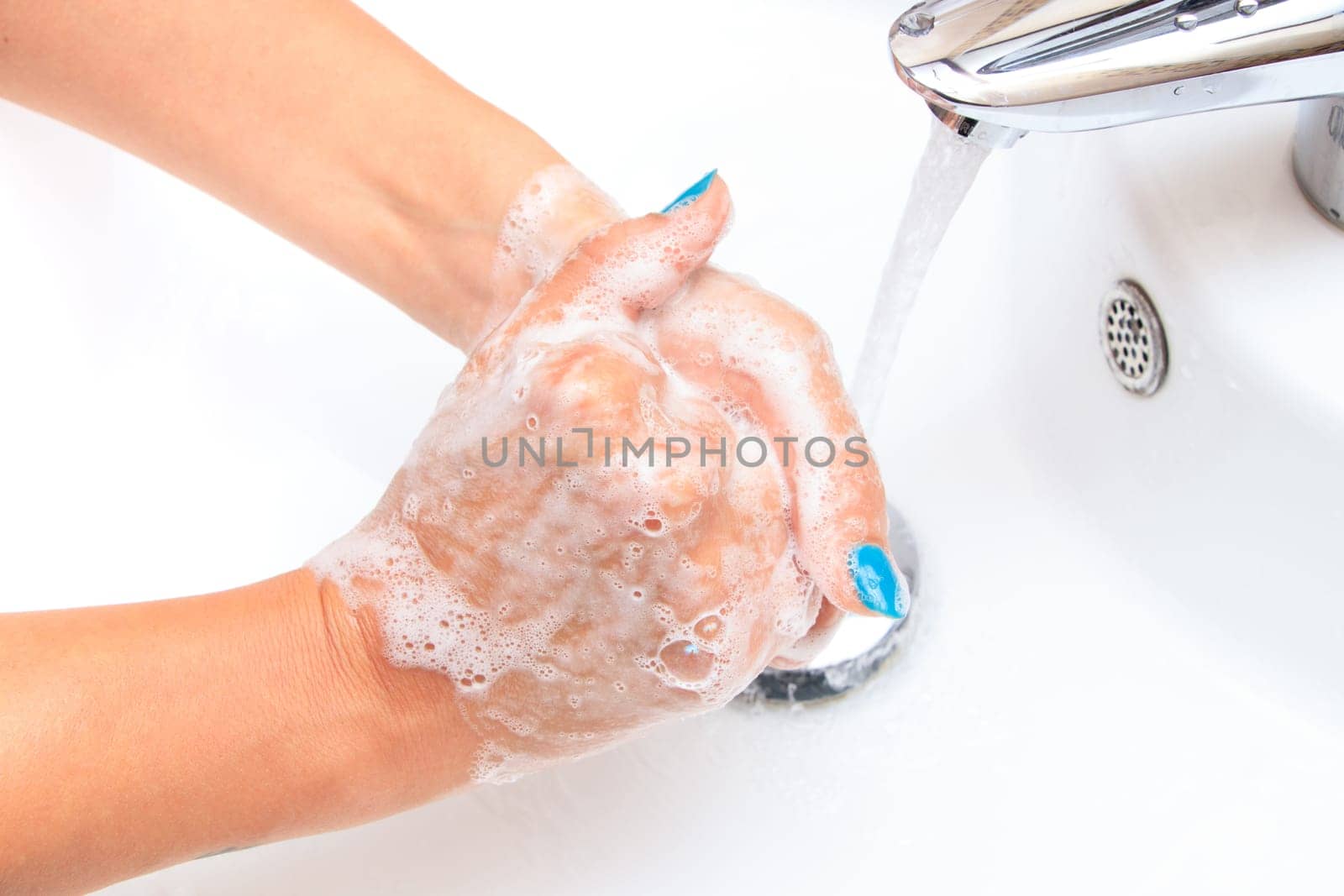Female hands under running water in the sink