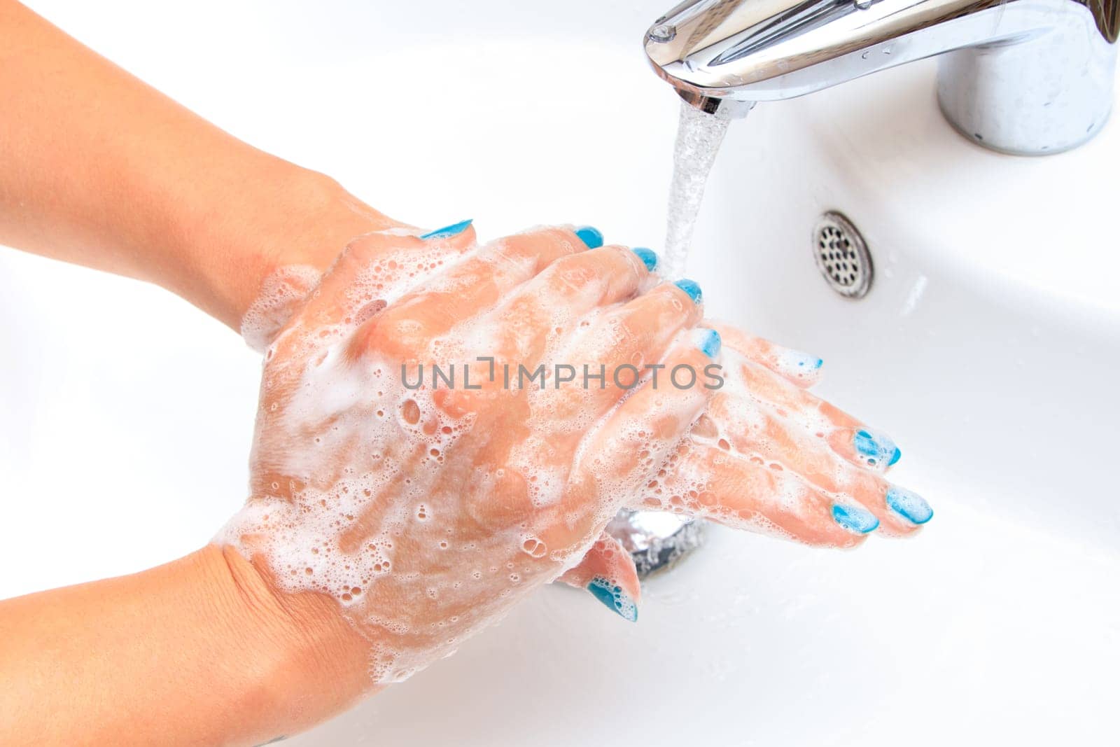 Female hands under running water in the sink