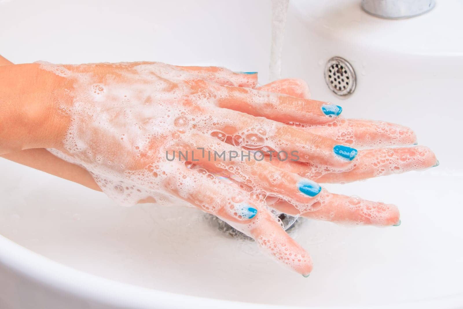 Female hands under running water in the sink