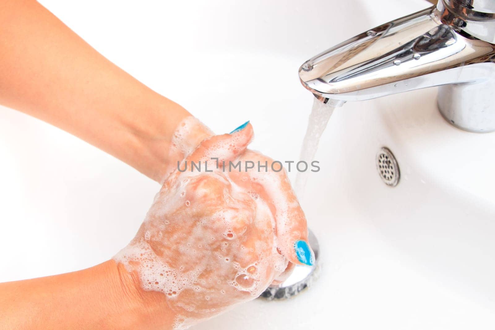 Female hands under running water in the sink