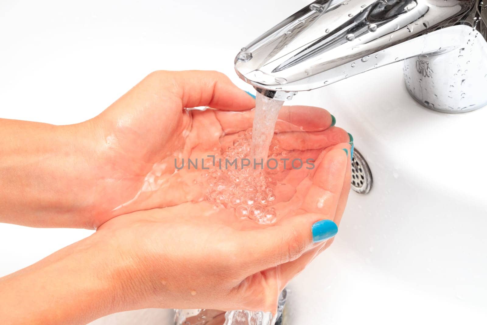 Female hands under running water in the sink