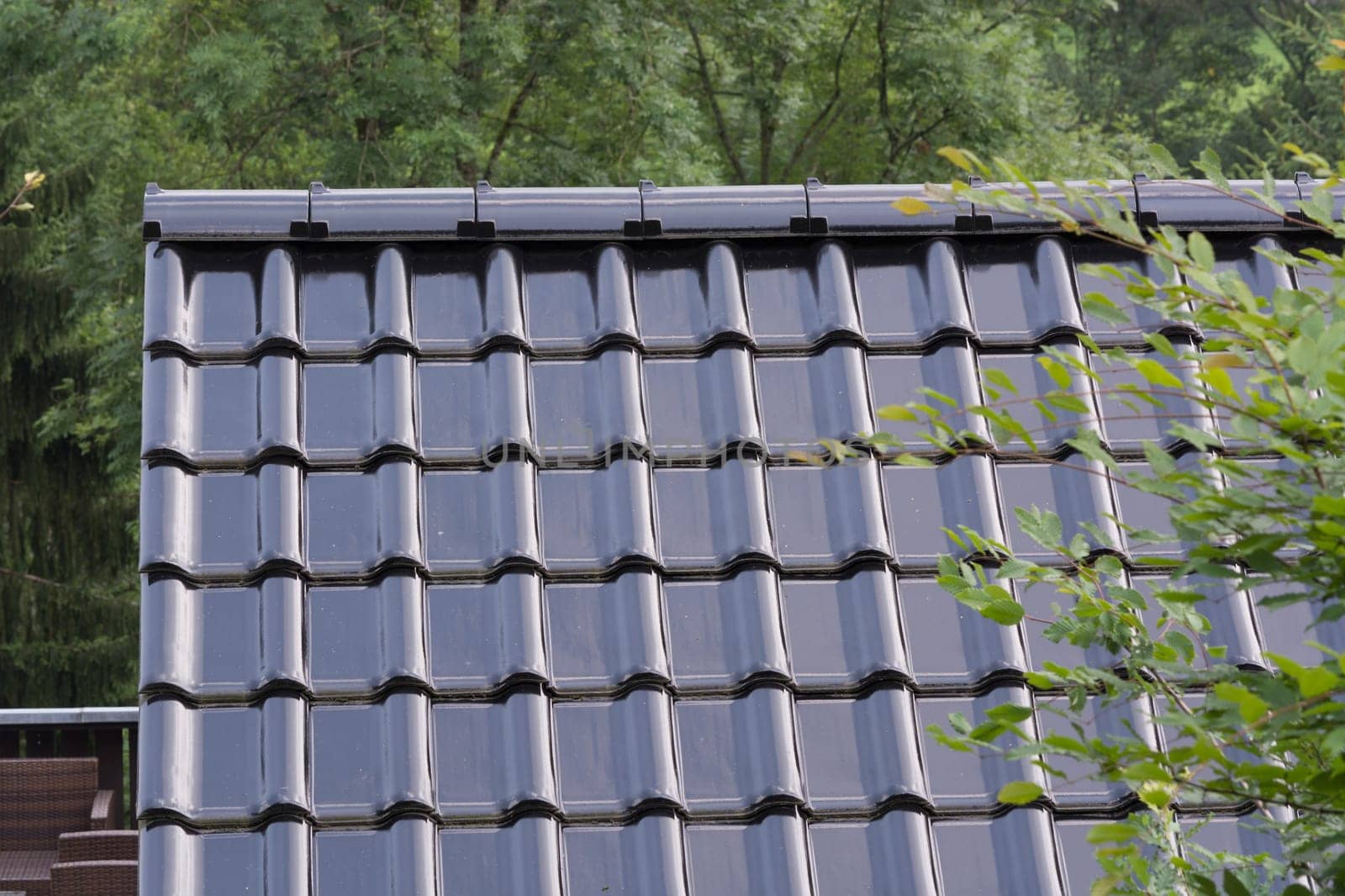 Modern roof with PVC coated black roof tiles with brick effect.