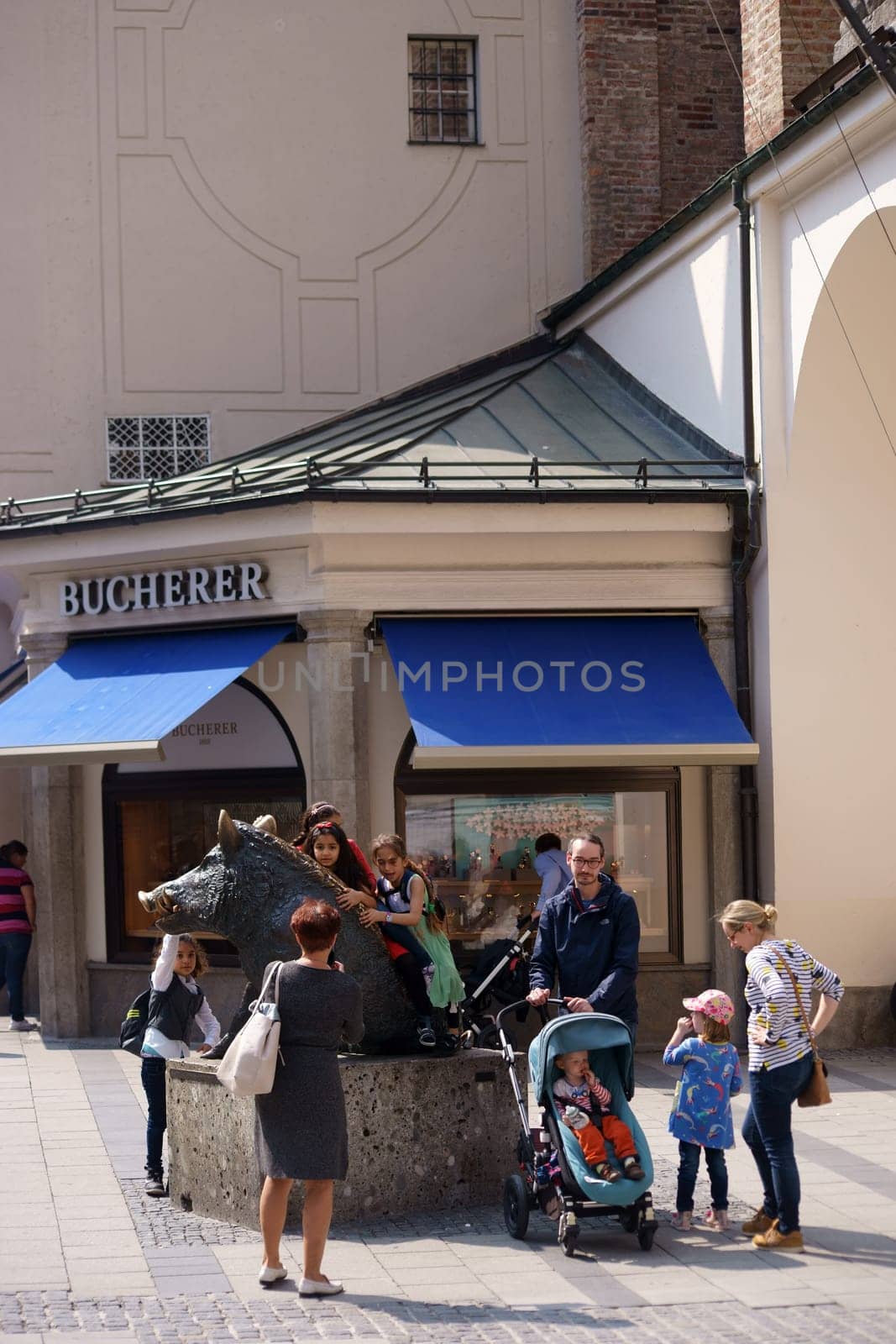 Munich, Germany - June 29, 2018: Children are playing a bronze sculpture of a wild boar in front of the hunting and fishing museum on June 29, 2018 in Munich..