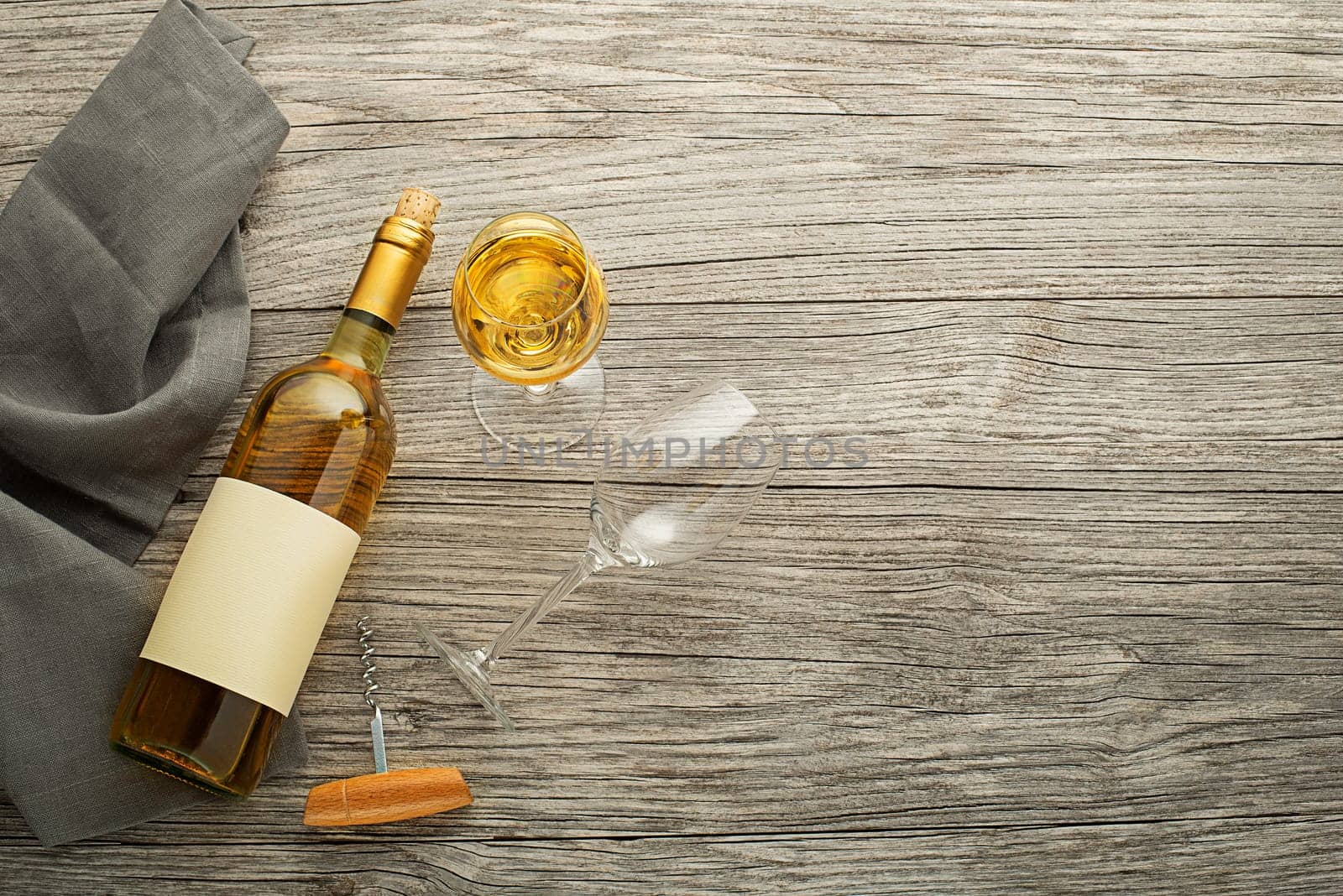 Bottle of white wine with label on old board. Glass of wine and cork. Wine bottle mockup. Top view