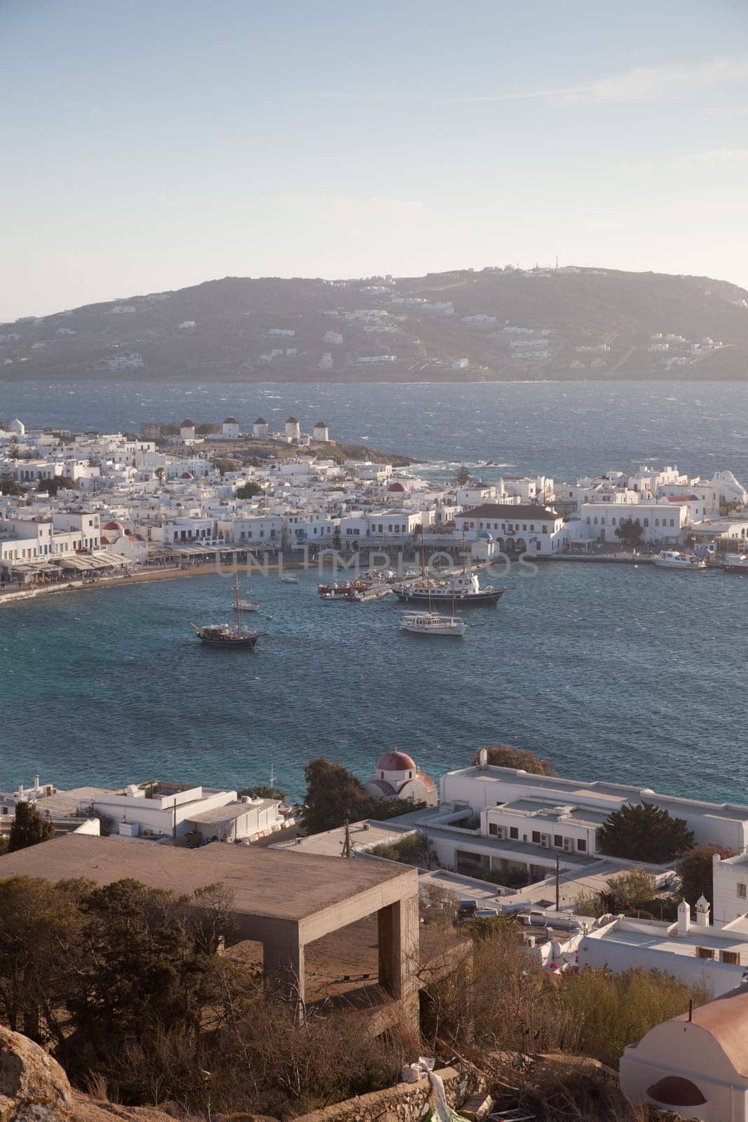 panoramic view of the Mykonos town harbor with famous windmills from the above hills on a sunny summer day, Mykonos, Cyclades, Greece
