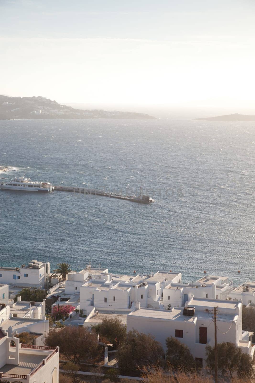 panoramic view of the Mykonos town harbor with famous windmills from the above hills on a sunny summer day, Mykonos, Cyclades, Greece