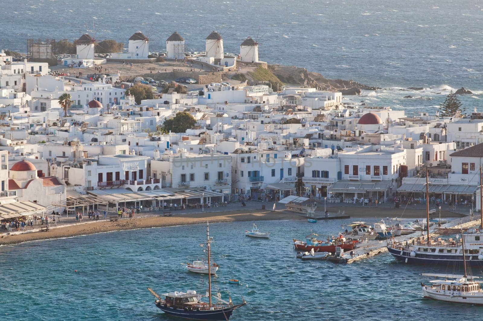 panoramic view of the Mykonos town harbor with famous windmills from the above hills on a sunny summer day, Mykonos, Cyclades, Greece