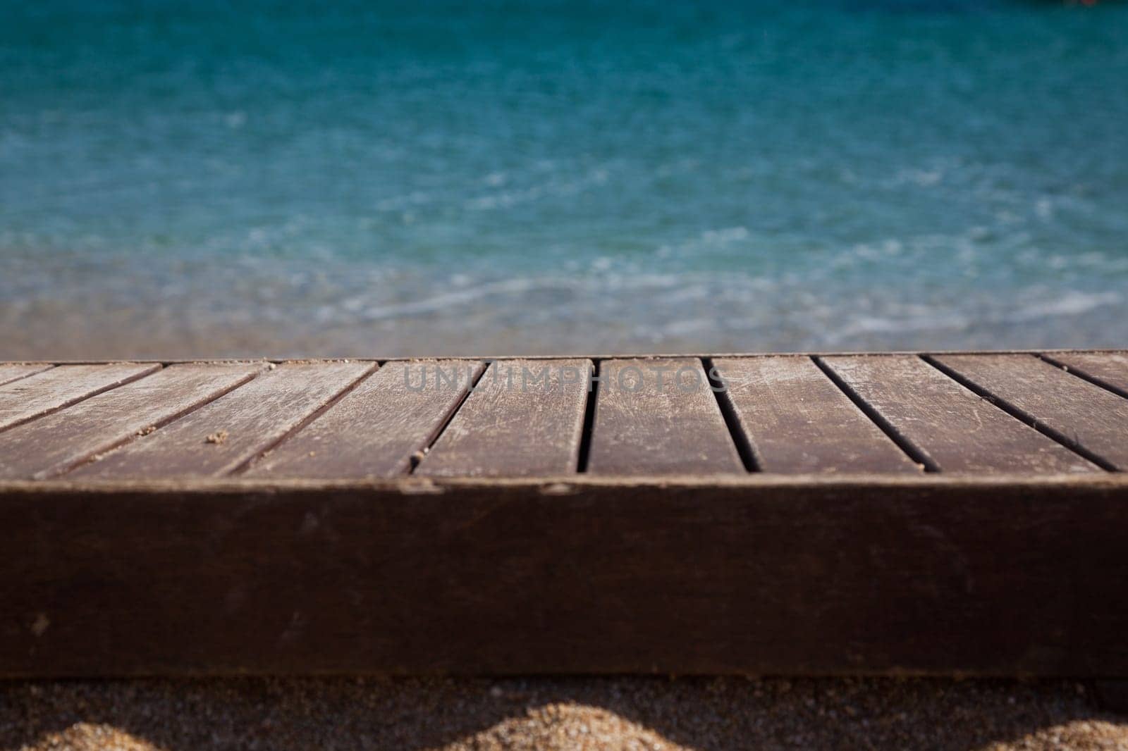 wooden plank in sand and blue sea in the background