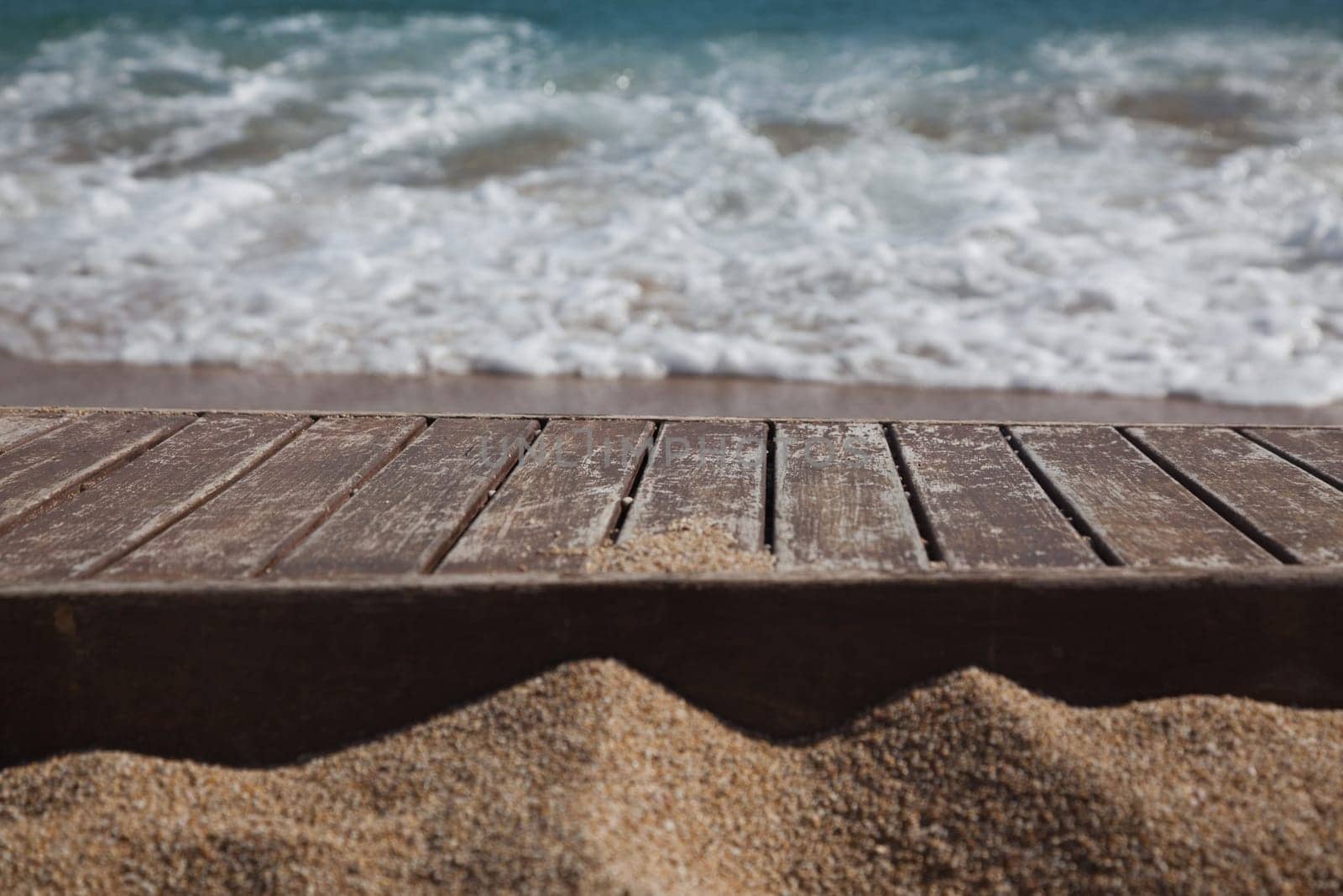 wooden plank in sand and blue sea in the background