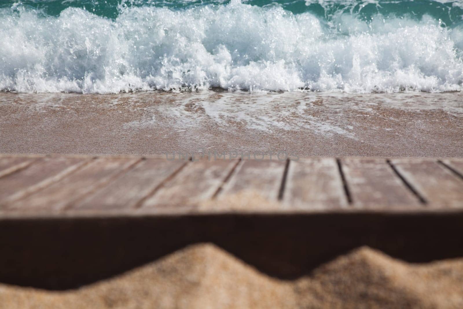 wooden plank in sand and blue sea in the background