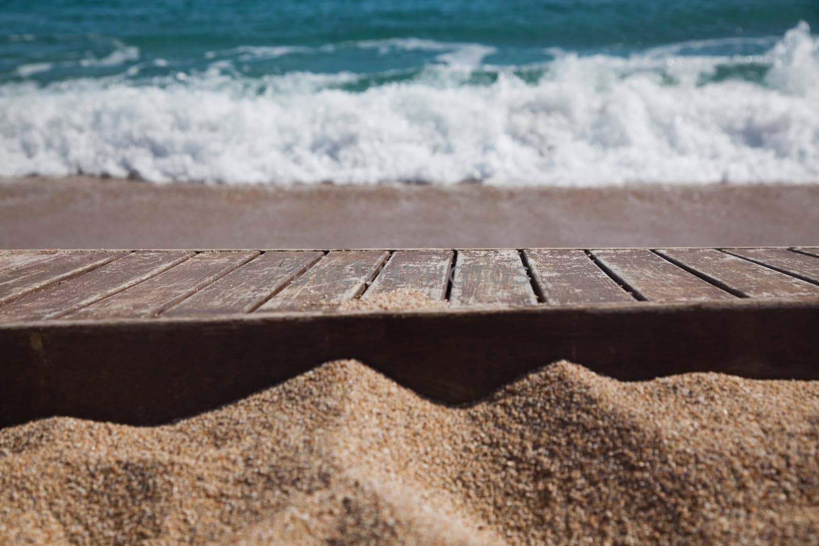 wooden plank in sand and blue sea in the background