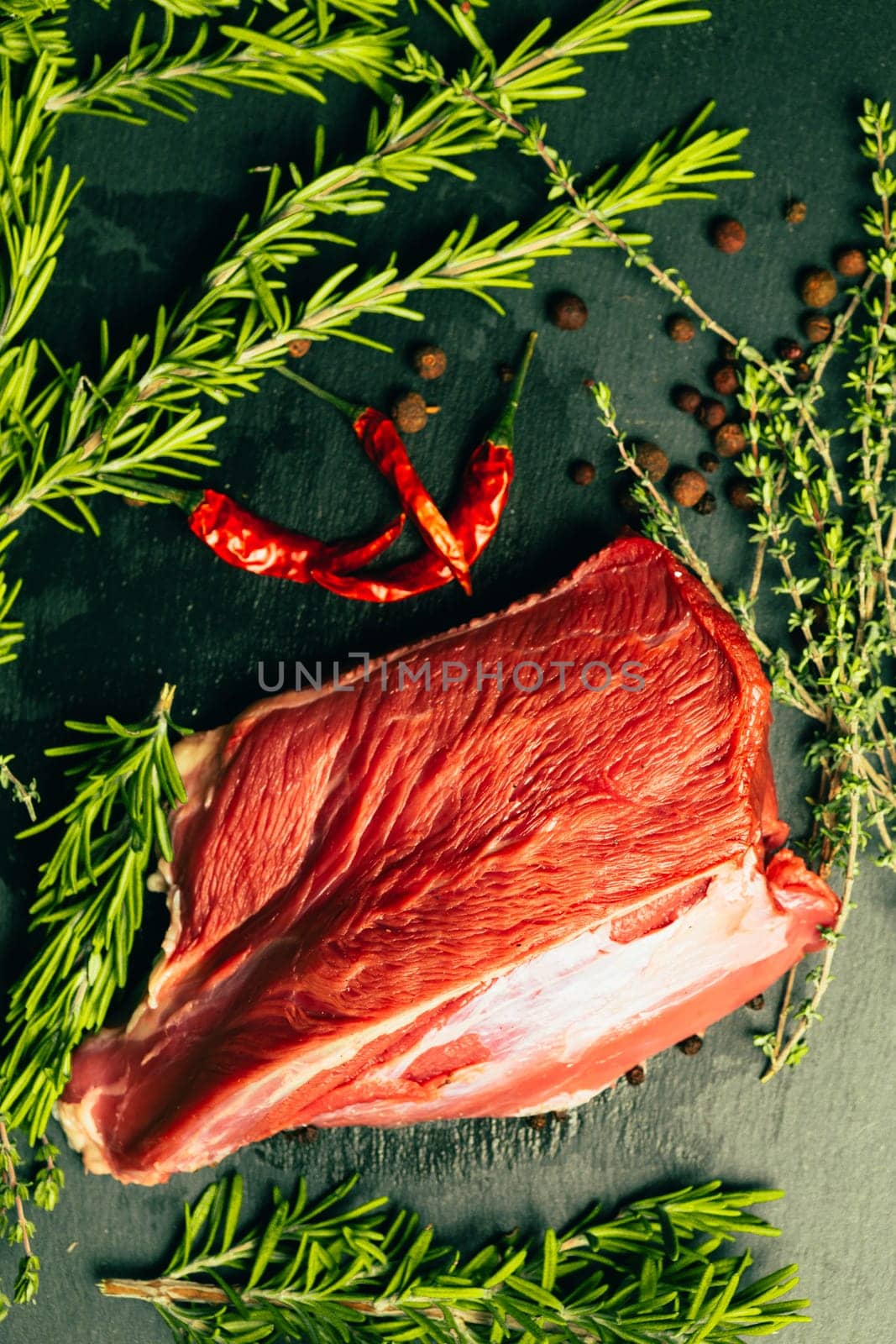 raw beef meat with spices on slate stone kitchen board.