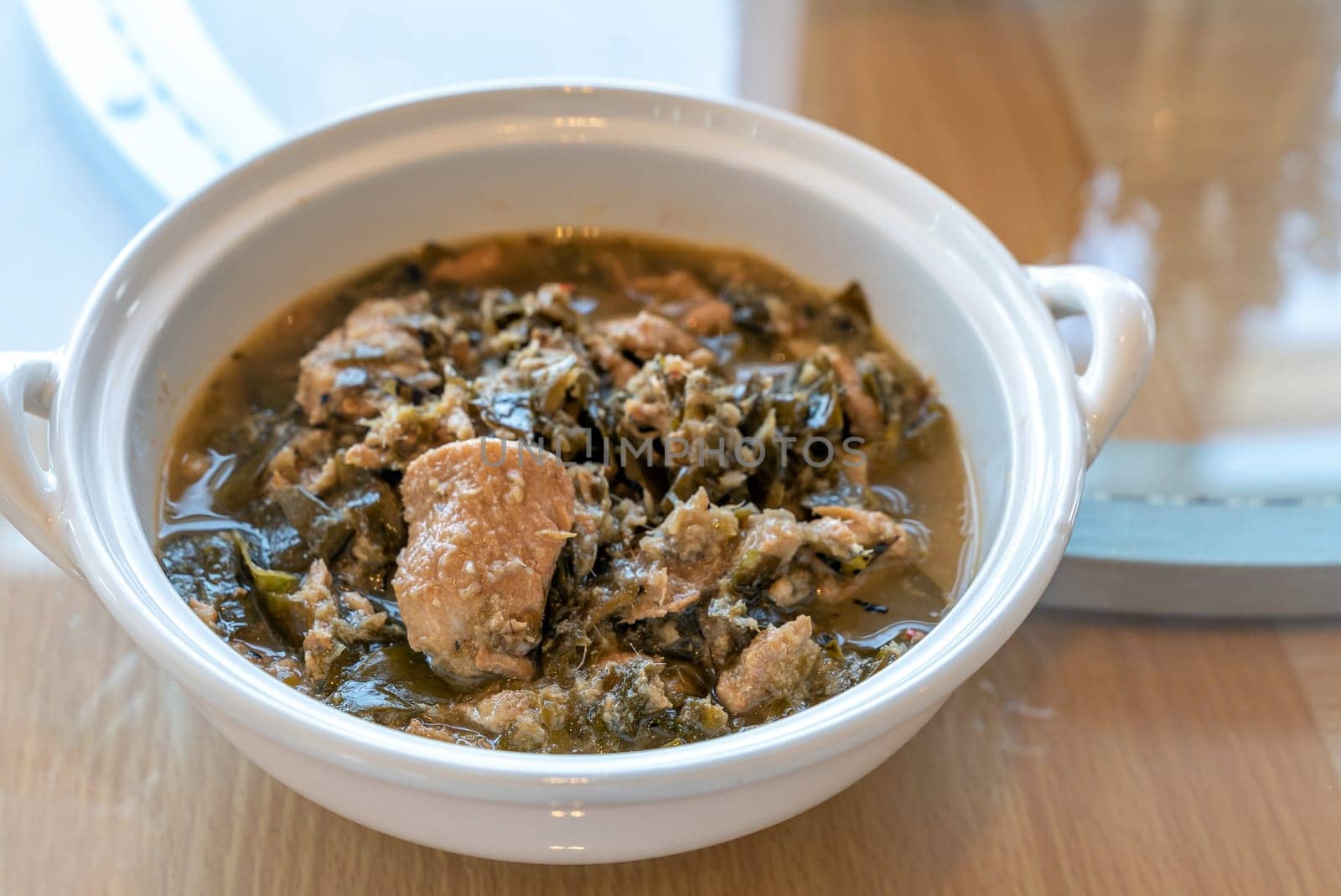 Thai Chamuang pork soup, pork with cowa leaf, thai east traditional food cuisine in white bowl on wooden background
