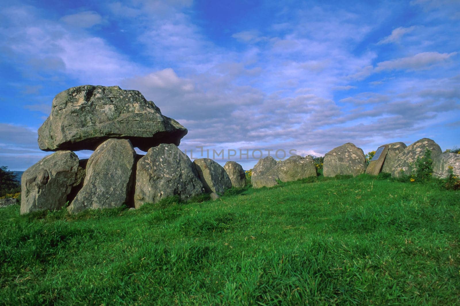 Horizontal view of Tomb 7 at Carrowmore, the largest and among the oldest cemeteries of megalithic tombs in Ireland, located in a hilly area, blue sky and green grass