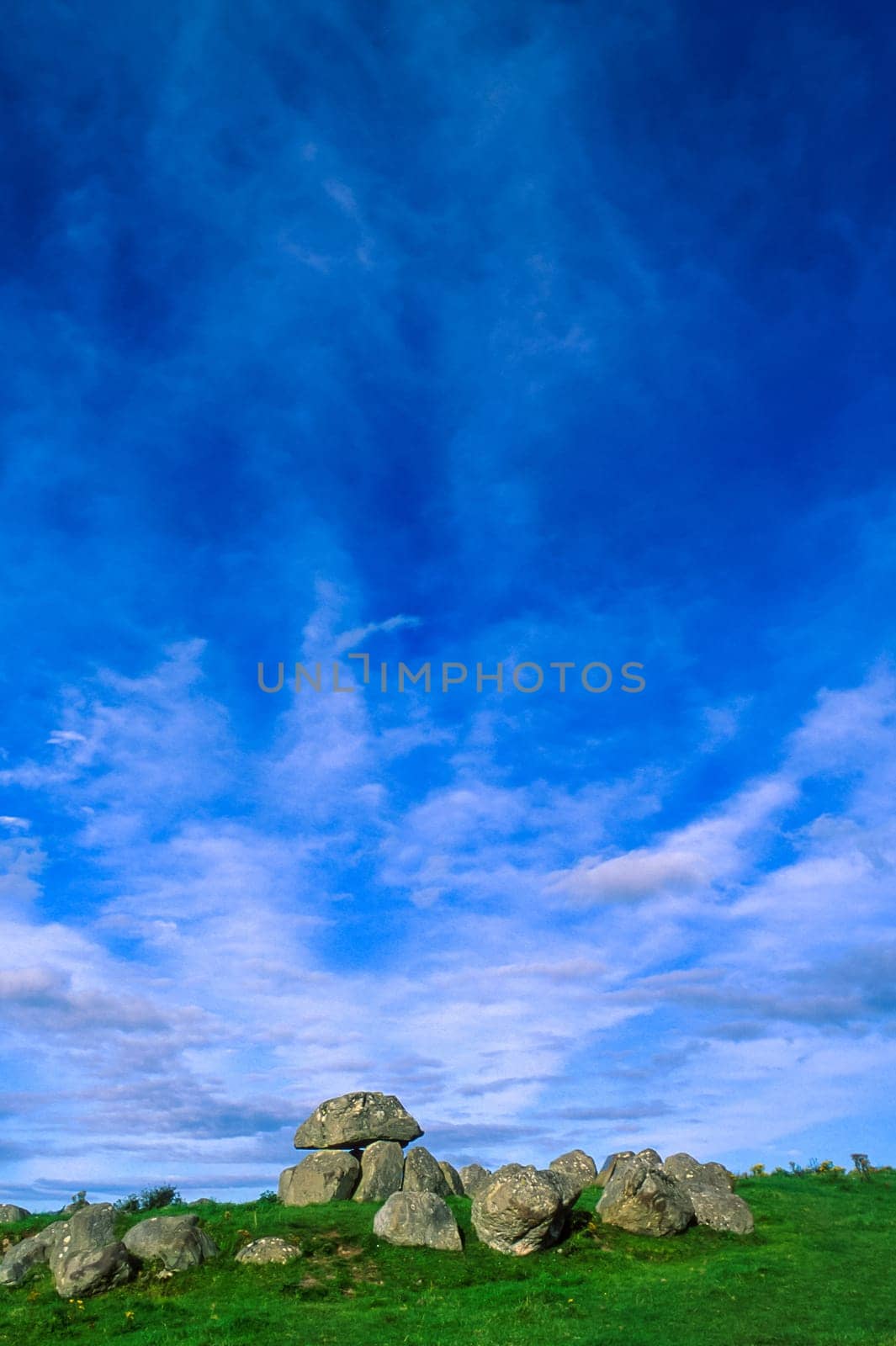 Vertical view with Carrowmore Tomb 7 in the foreground, the most intact example of dolmen located in the oldest megalithic complex of Ireland, near Sligo, landscape with blue sky and clouds